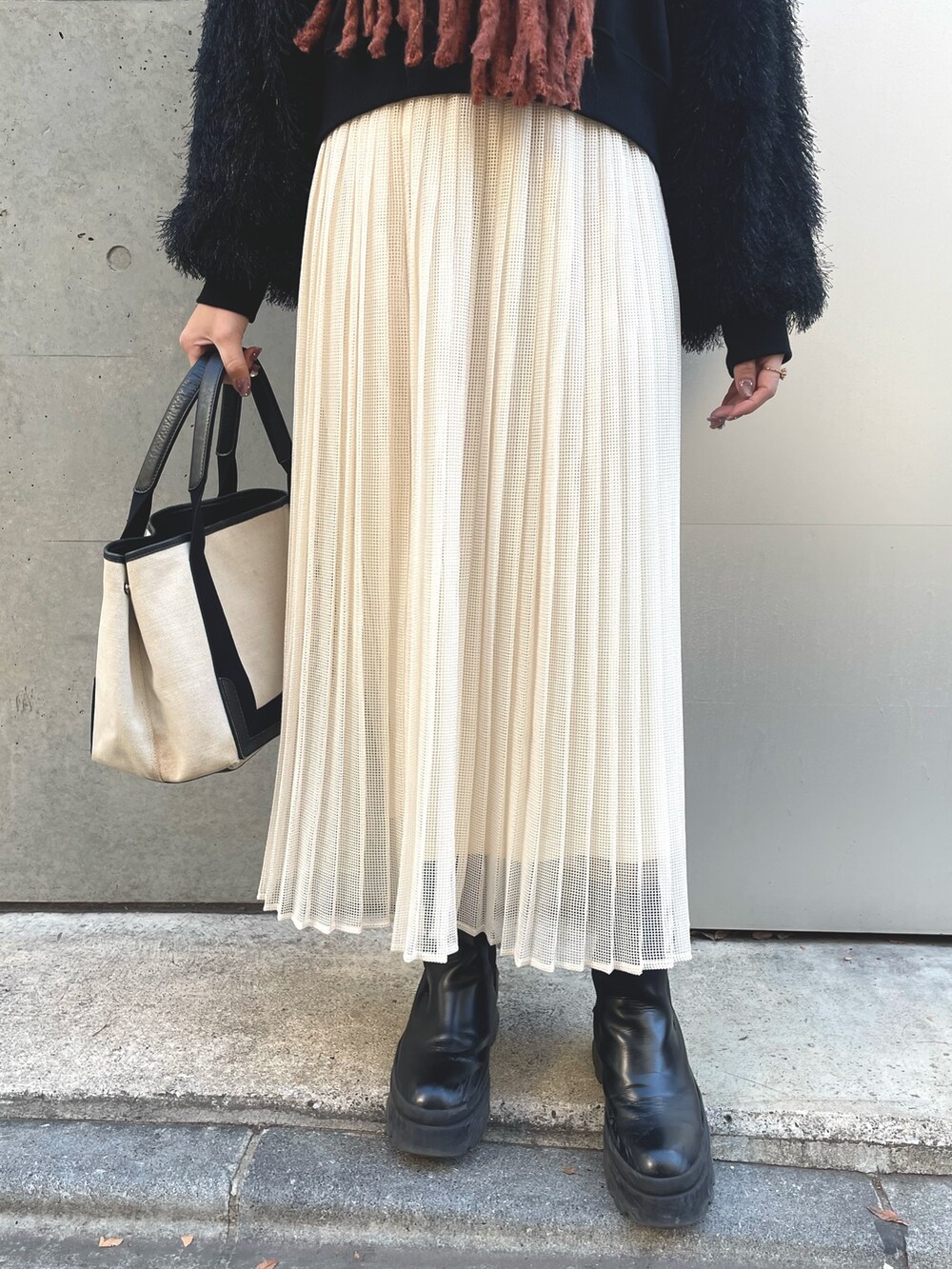 ホワイト系のスカート、ブラック系のスウェット、ベージュ系のトートバッグを着用したレディースの冬コーディネートの4枚目の写真