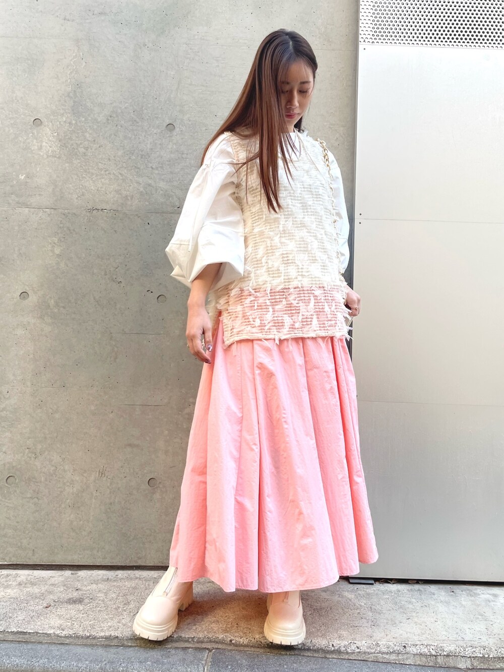 ピンク系のスカート、ホワイト系のシャツ/ブラウス、ホワイト系のベストを着用したレディースの冬コーディネートの2枚目の写真