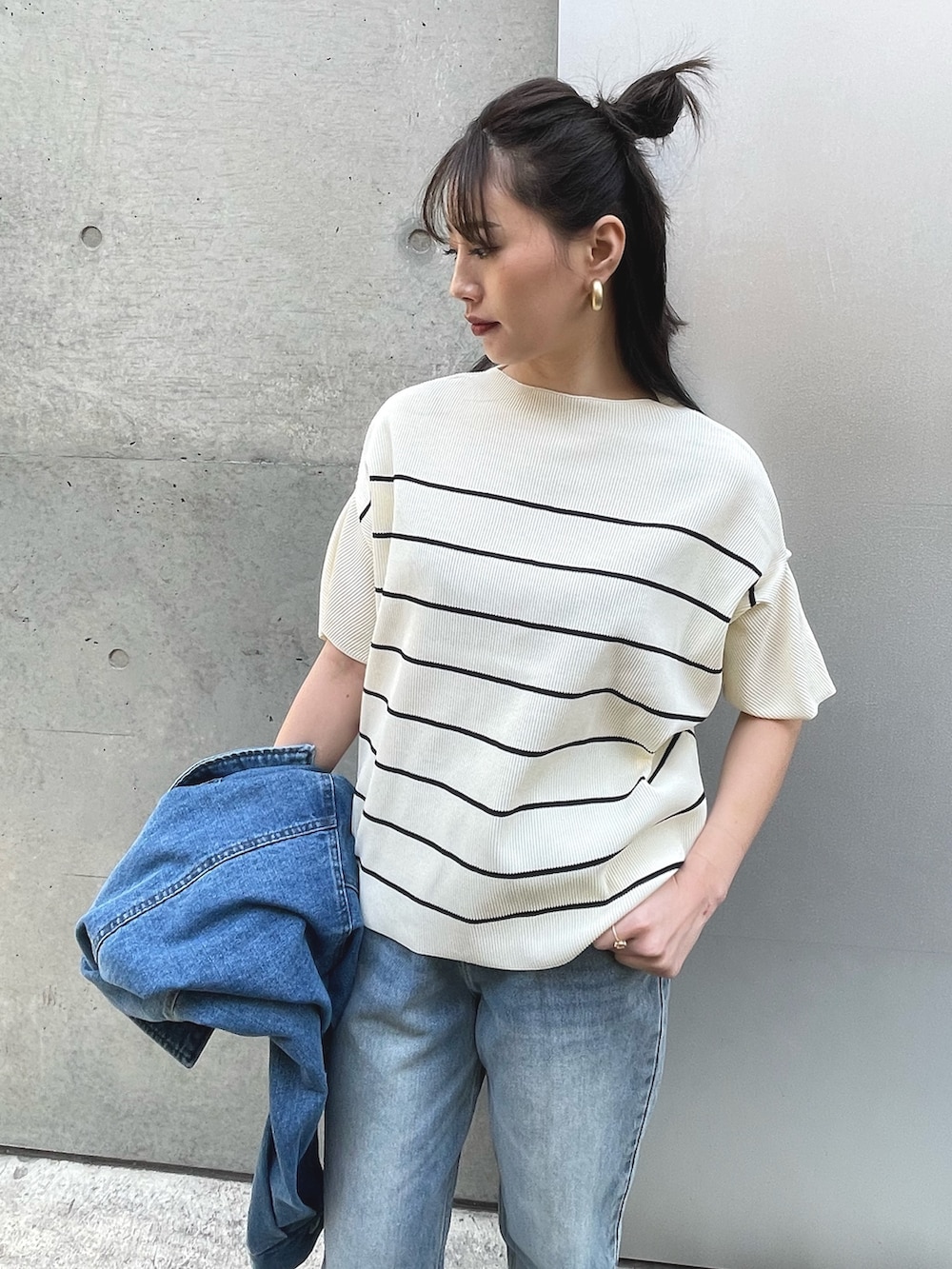 ブルー系のデニムジャケット、ブラック系のスニーカー、ブルー系のデニムパンツを着用したレディースの春コーディネートの4枚目の写真