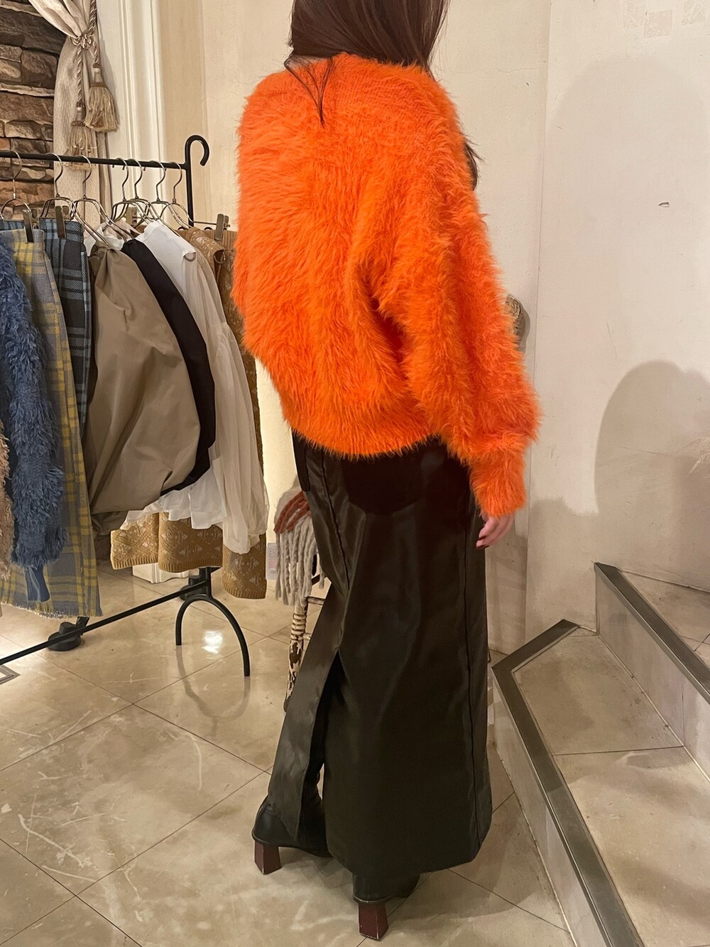 オレンジ系のニット/セーター、ブラック系のスカートを着用したレディースの秋コーディネートの3枚目の写真