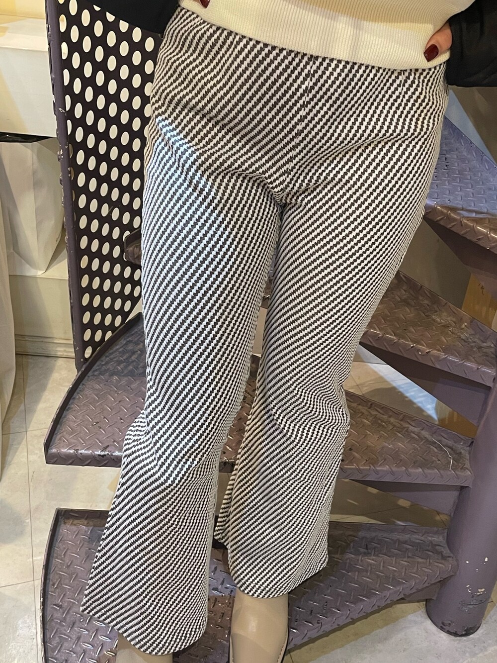 ブラック系のその他アウター、ホワイト系のニット/セーター、ベージュ系のショルダーバッグを着用したレディースの秋コーディネートの6枚目の写真