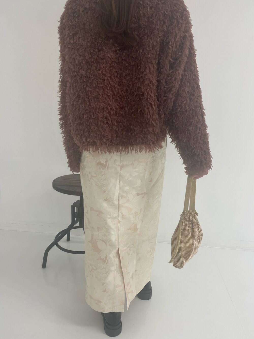 ゴールド系のトートバッグ、ホワイト系のスカート、ブラウン系のTシャツ/カットソーを着用したレディースの冬コーディネートの5枚目の写真