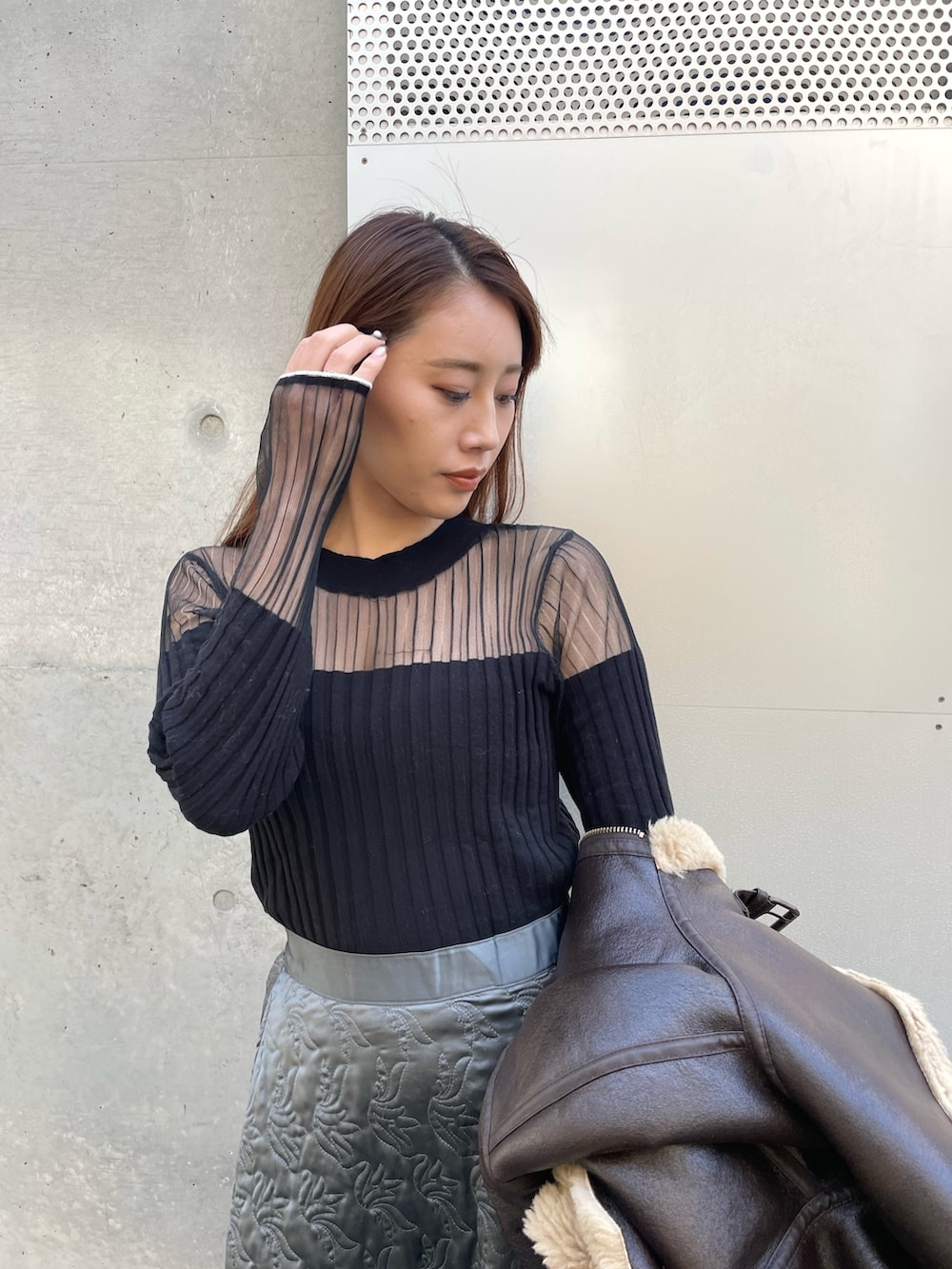 ブラウン系のジャケット/アウター、グリーン系のスカート、ブラック系のニット/セーターを着用したレディースの冬コーディネートの3枚目の写真