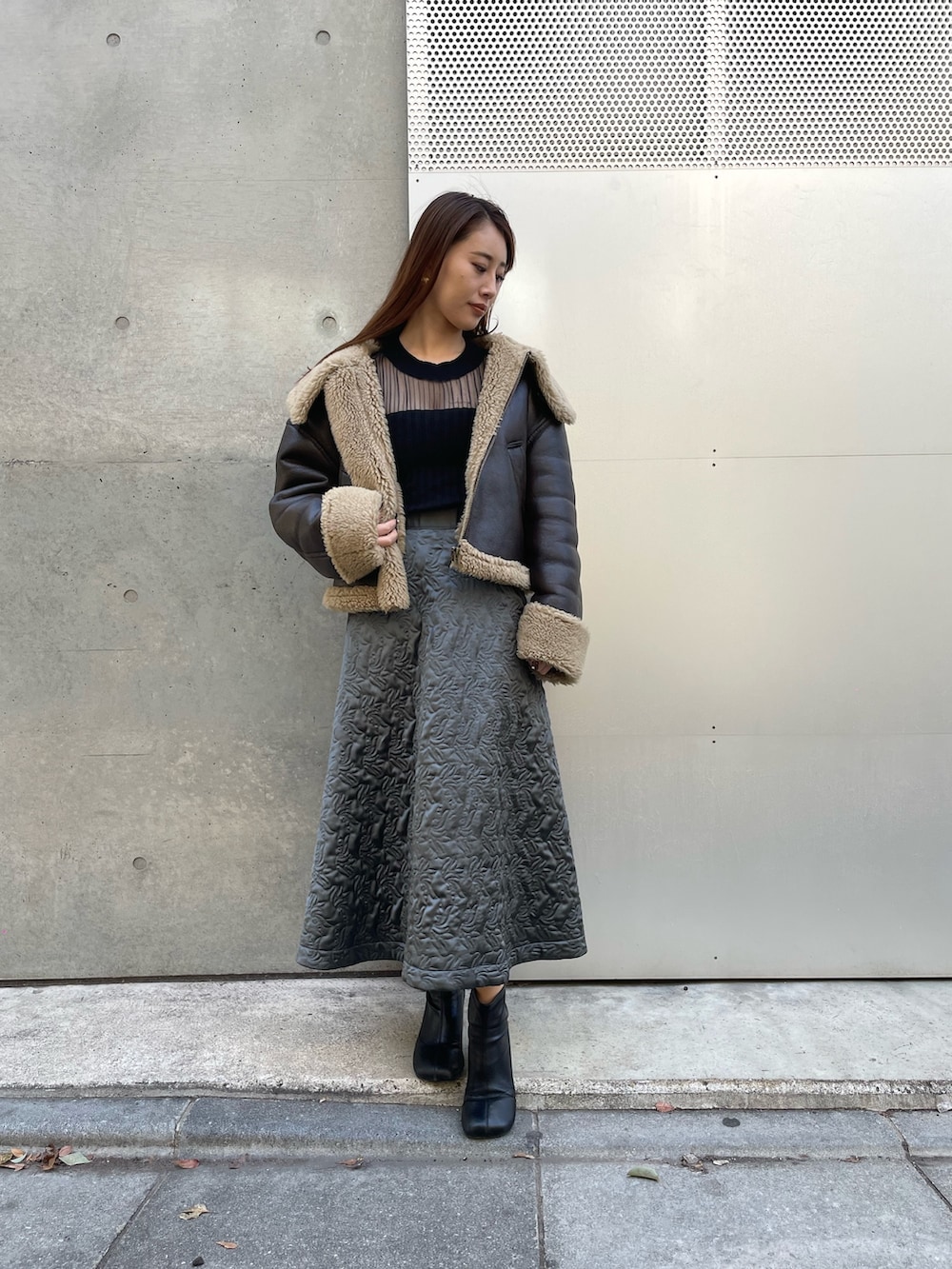 ブラウン系のジャケット/アウター、グリーン系のスカート、ブラック系のニット/セーターを着用したレディースの冬コーディネートの2枚目の写真