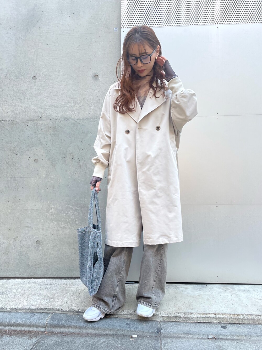 ベージュ系のトレンチコート、ブラック系のデニムパンツ、ホワイト系のスニーカーを着用したレディースの春コーディネートの2枚目の写真
