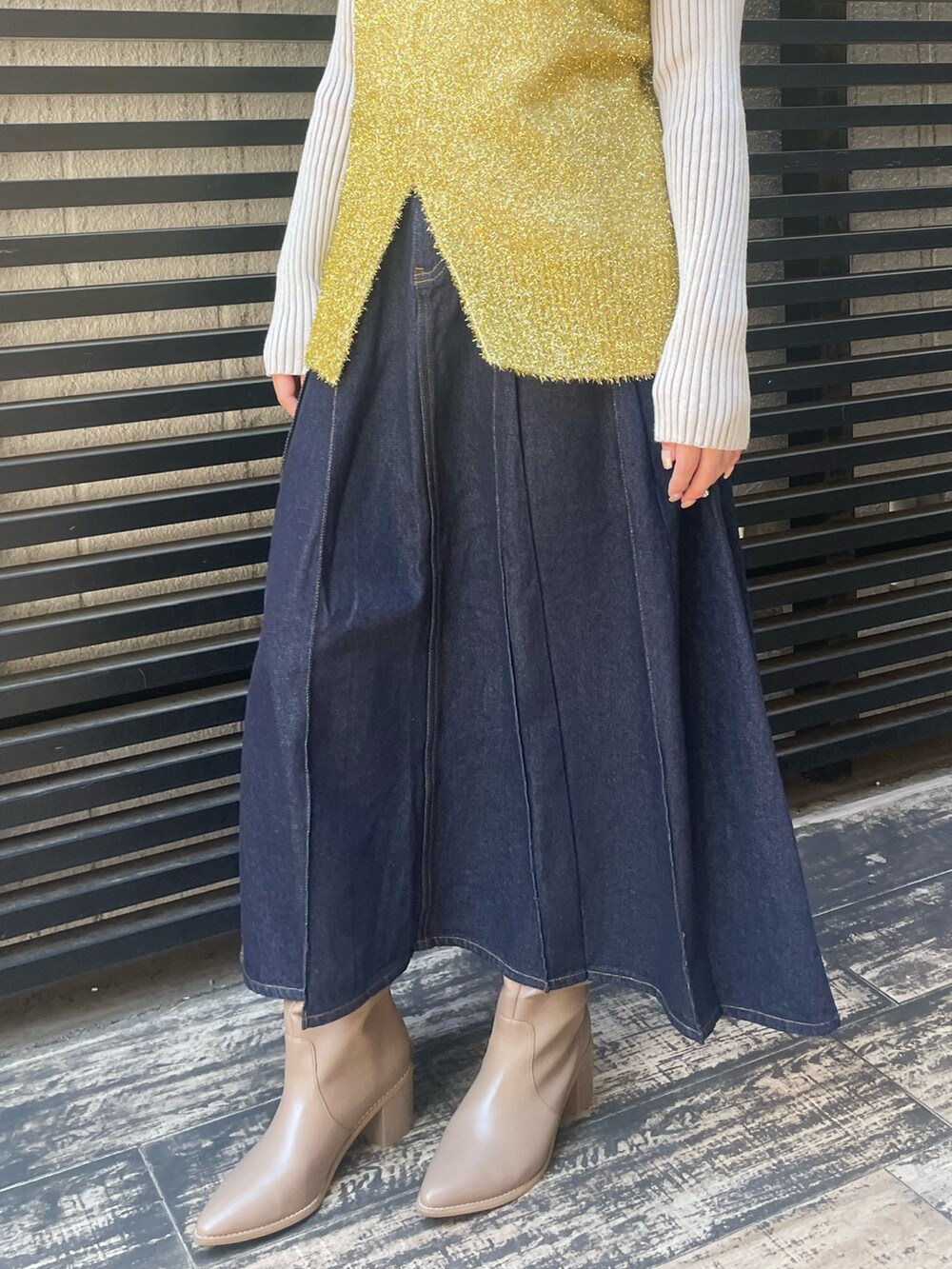 ブルー系のデニムスカート、ホワイト系のニット/セーター、ゴールド系のベストを着用したレディースの冬コーディネートの10枚目の写真