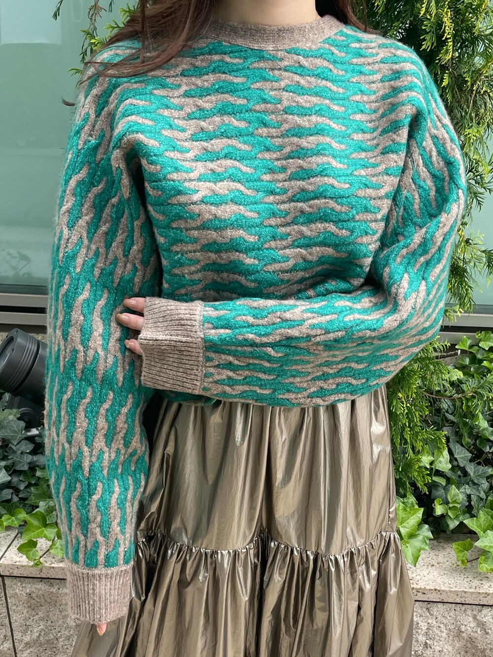 グリーン系のニット/セーター、ゴールド系のスカートを着用したレディースの秋コーディネートの6枚目の写真