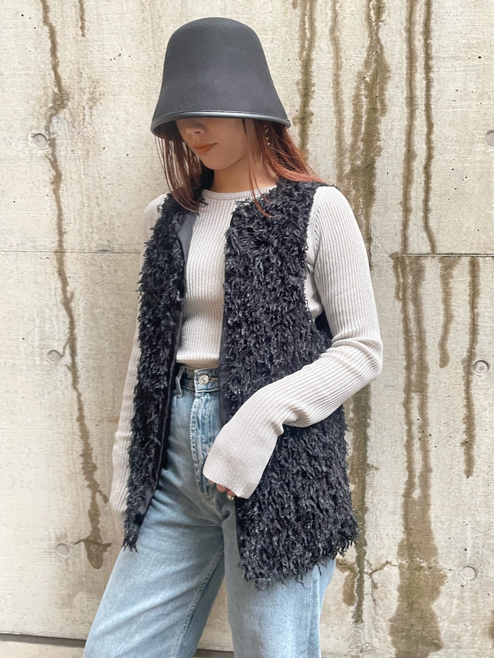 ブラック系のベスト、ホワイト系のニット/セーター、ブラック系のハットを着用したレディースの冬コーディネートの2枚目の写真