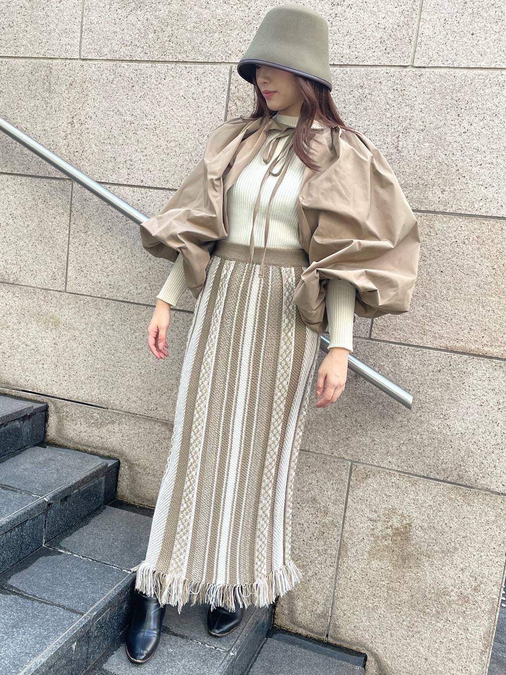 ベージュ系のスカート、ブラウン系のカーディガン/ボレロ、グリーン系のハットを着用したレディースの秋コーディネートの2枚目の写真
