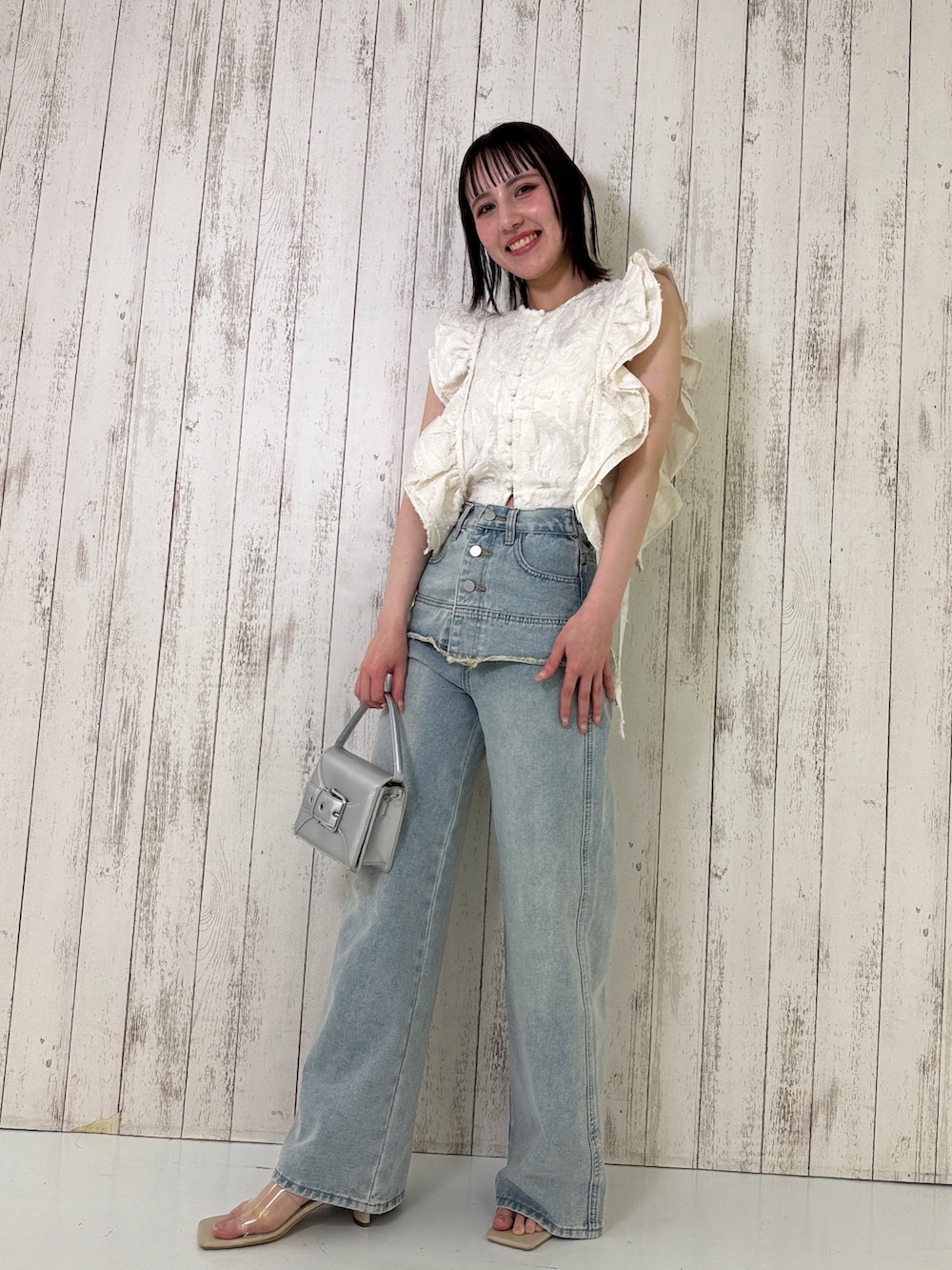 ホワイト系のベスト、ブルー系のデニムパンツ、シルバー系のショルダーバッグを着用したレディースの春コーディネートの3枚目の写真