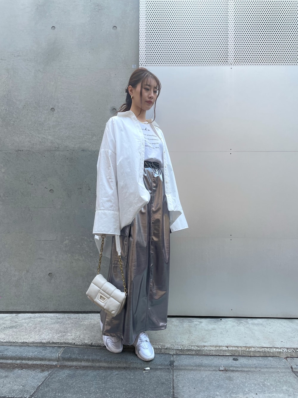 ホワイト系のハンドバッグ、ホワイト系のスニーカー、シルバー系のスカートを着用したレディースの春コーディネートの2枚目の写真