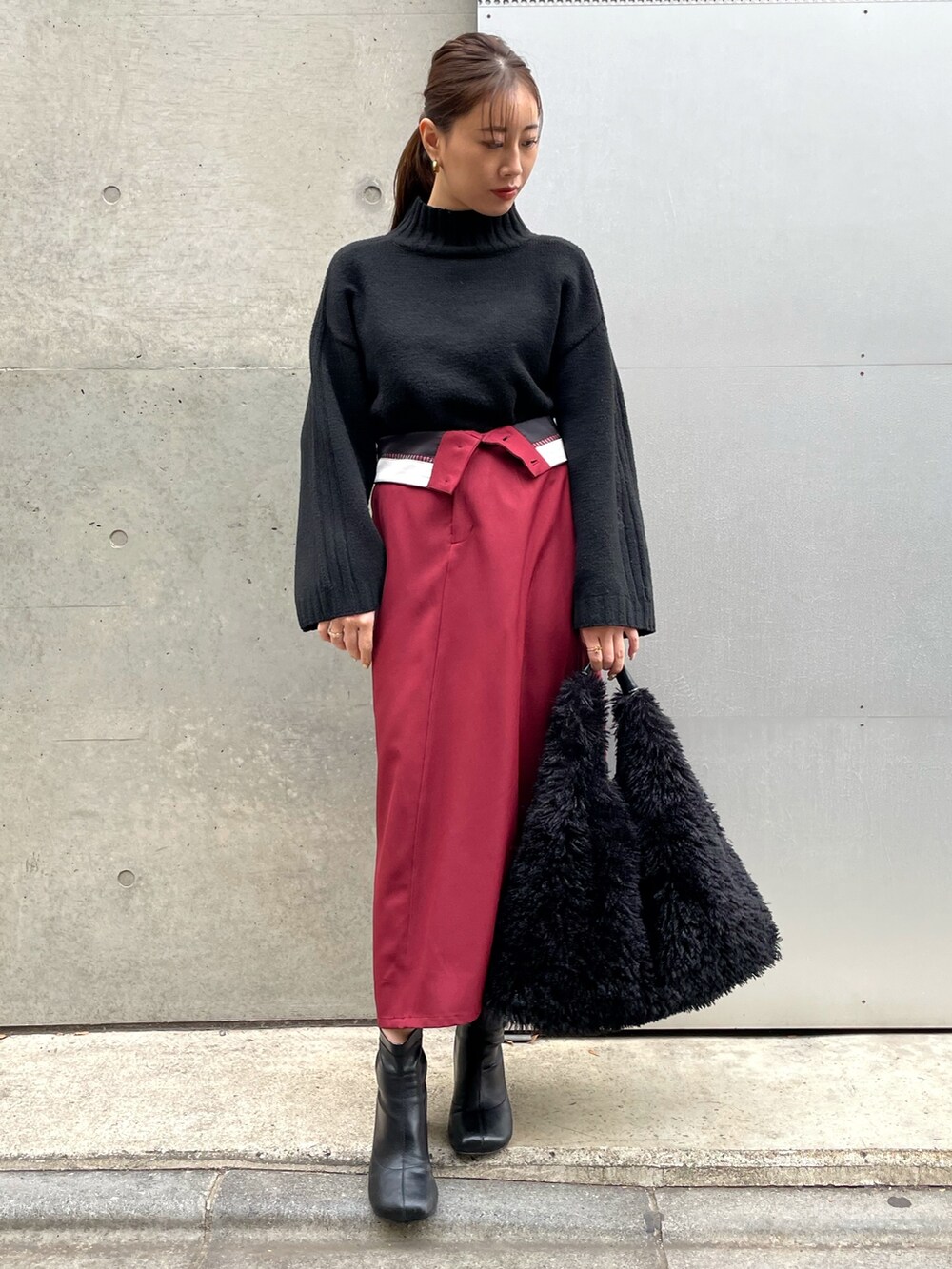 ブラック系のブーツ、レッド系のスカート、ブラック系のニット/セーターを着用したレディースの冬コーディネートの3枚目の写真
