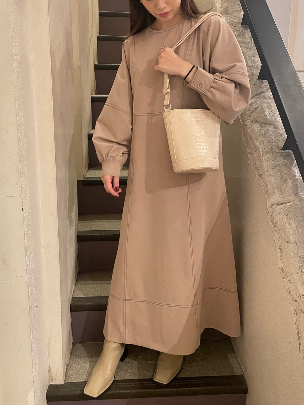 ホワイト系のショルダーバッグ、グレー系のワンピースを着用したレディースの冬コーディネートの2枚目の写真