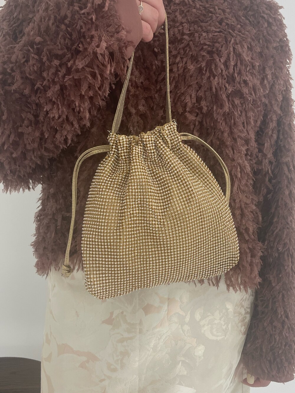 ゴールド系のトートバッグ、ホワイト系のスカート、ブラウン系のTシャツ/カットソーを着用したレディースの冬コーディネートの9枚目の写真