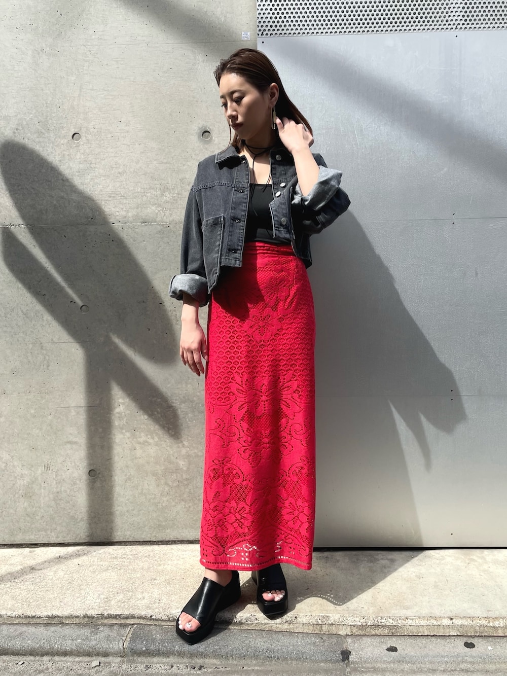 ブラック系のサンダル、レッド系のスカート、ブラック系のデニムジャケットを着用したレディースの春コーディネートの2枚目の写真