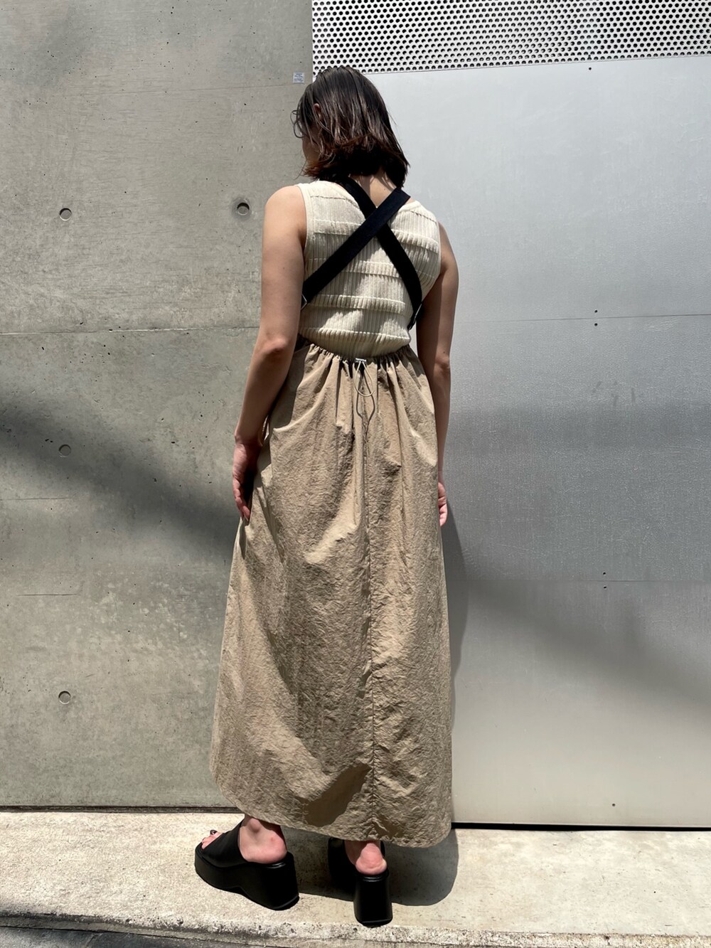 ホワイト系のニット/セーター、ベージュ系のワンピース、ブラック系のサンダルを着用したレディースの春コーディネートの2枚目の写真