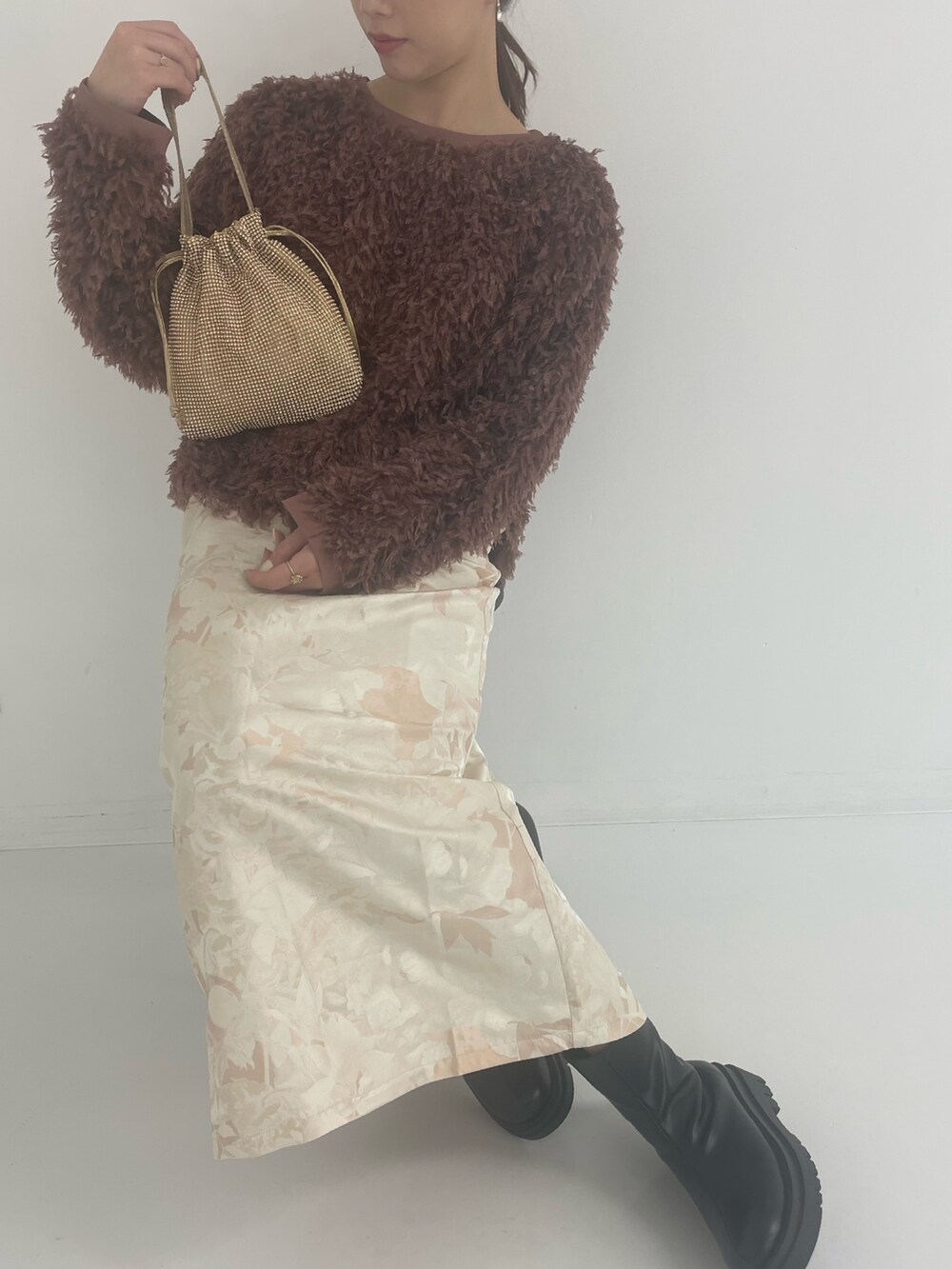 ゴールド系のトートバッグ、ホワイト系のスカート、ブラウン系のTシャツ/カットソーを着用したレディースの冬コーディネートの3枚目の写真