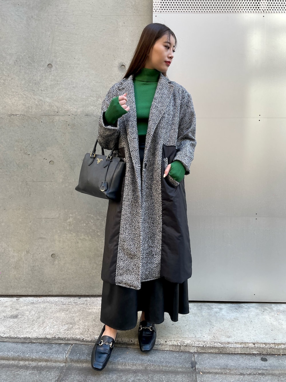 ブラック系のトレンチコート、ブラック系のスカート、ブラック系のハンドバッグを着用したレディースの冬コーディネートの3枚目の写真