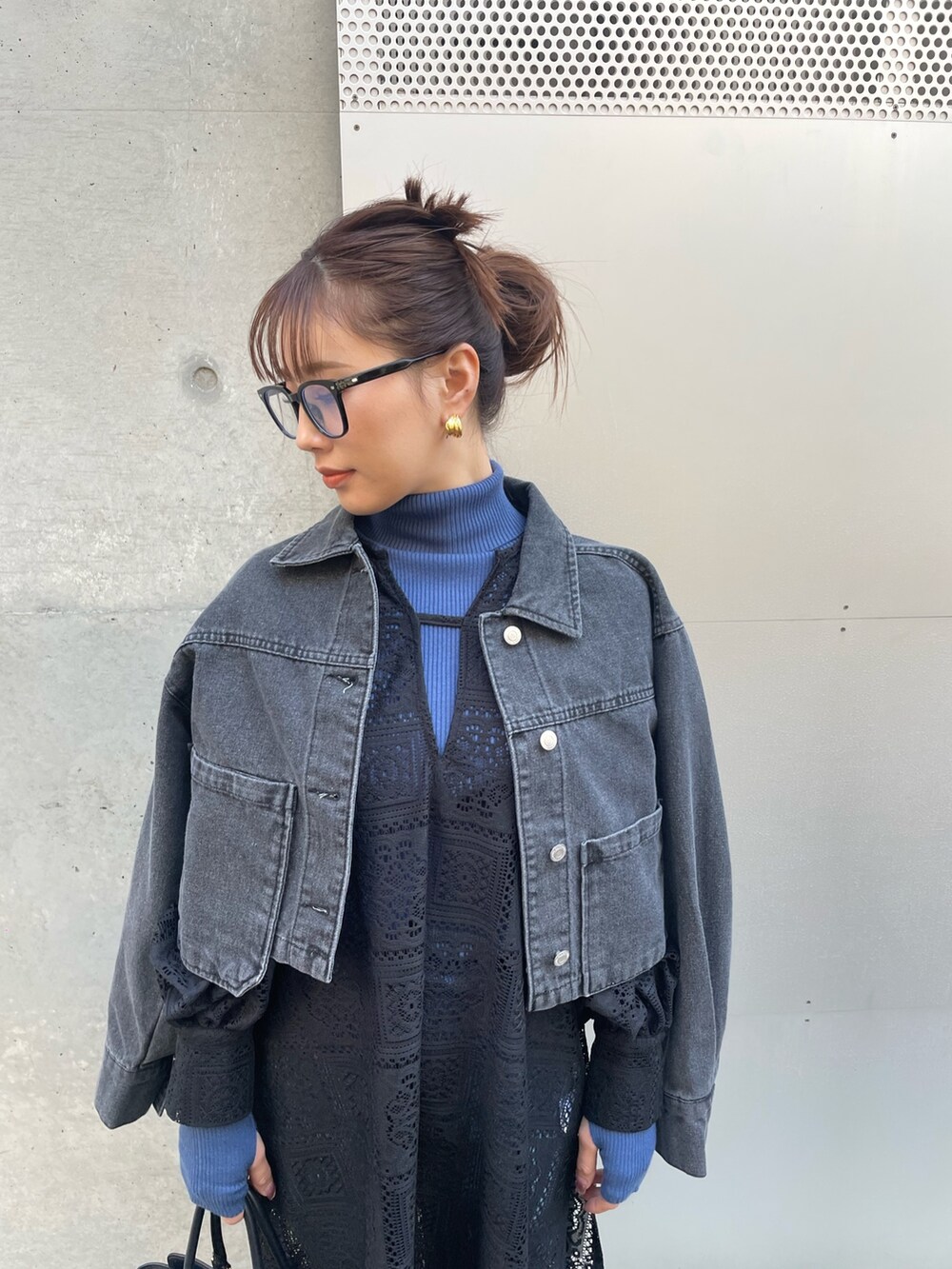 ブラック系のデニムジャケット、ブルー系のニット/セーター、ブラック系のワンピースを着用したレディースの冬コーディネートの3枚目の写真