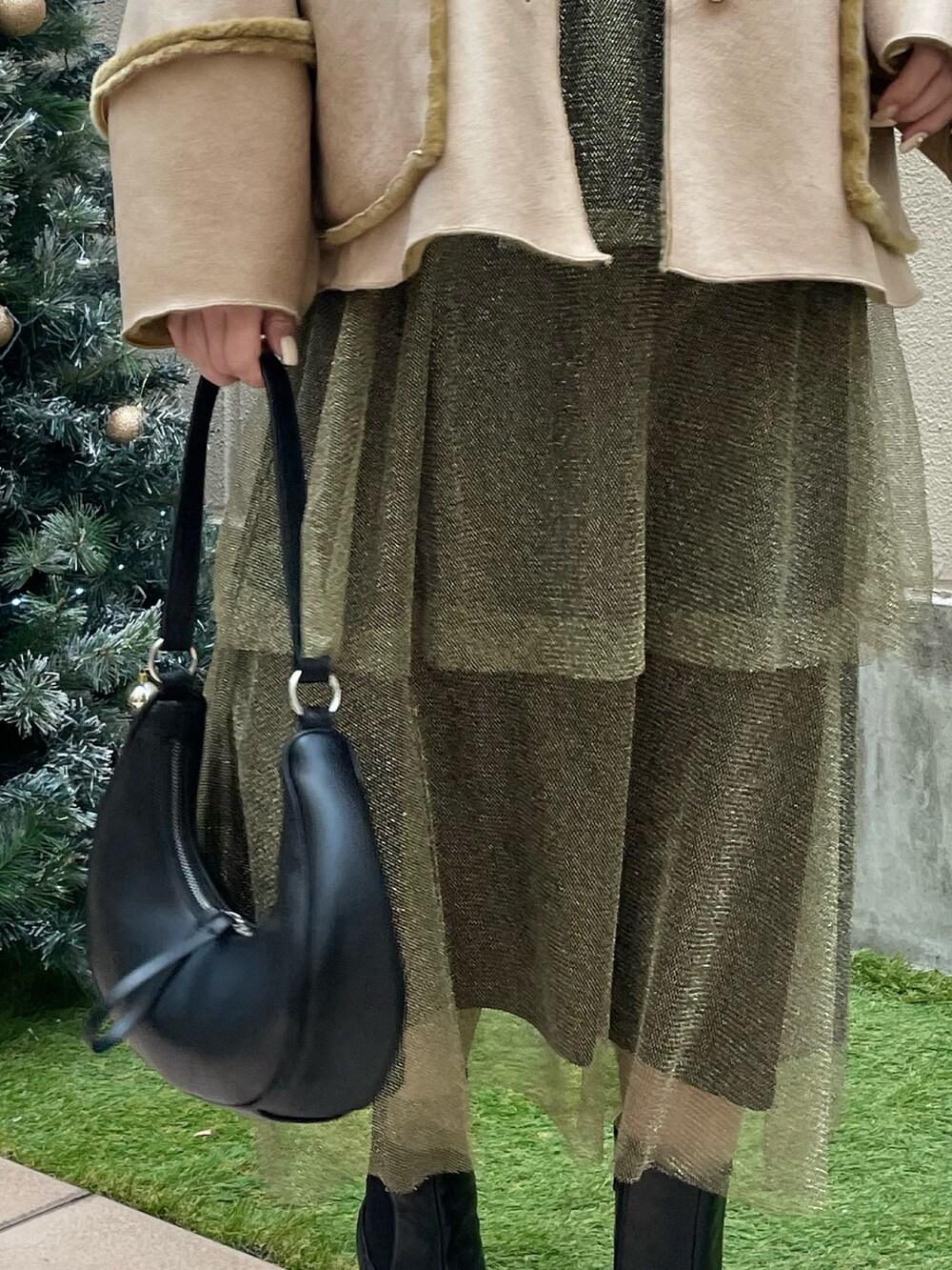 ゴールド系のスカート、ブラック系のショルダーバッグ、ブラック系のTシャツ/カットソーを着用したレディースの冬コーディネートの9枚目の写真