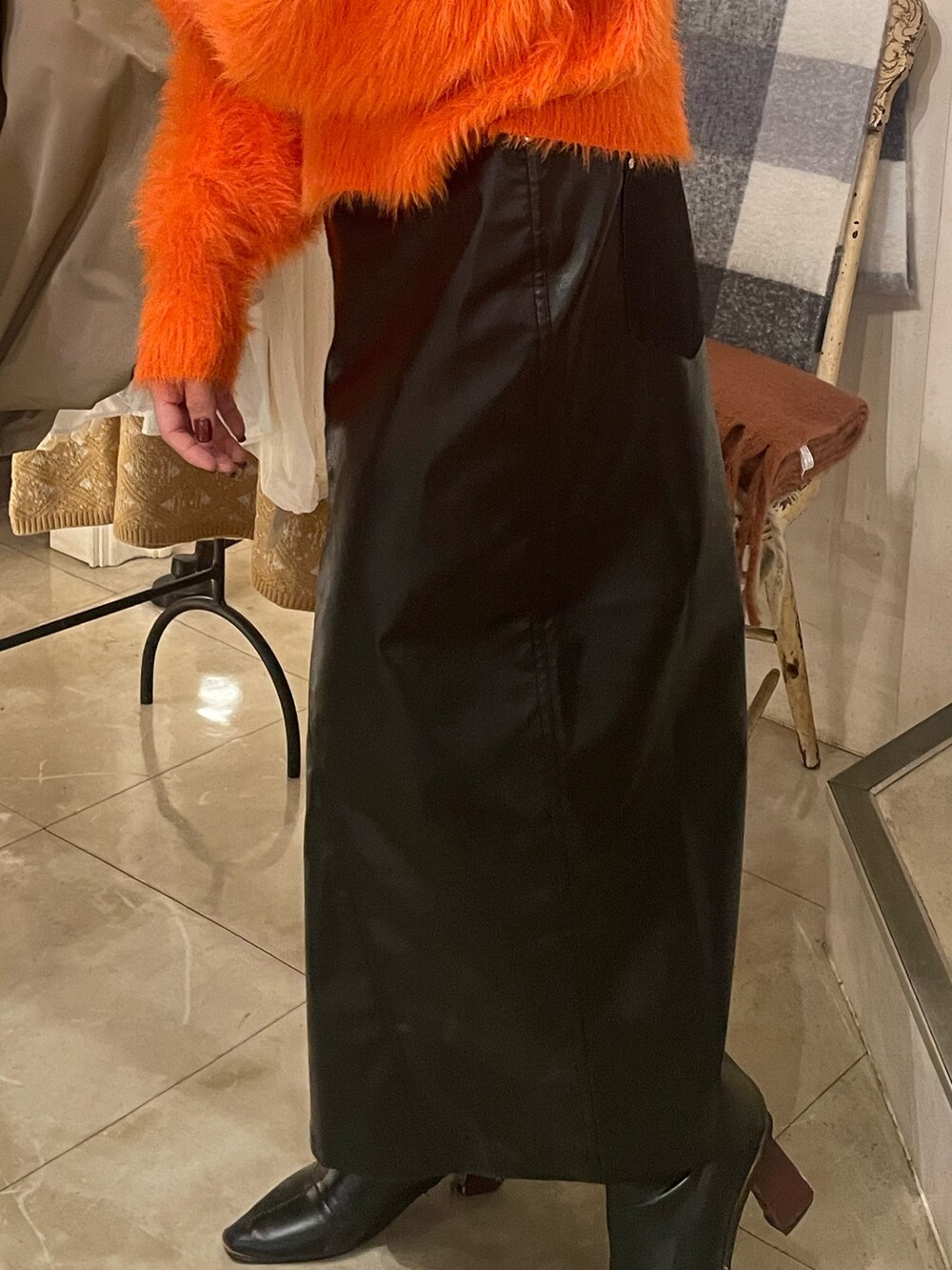 オレンジ系のニット/セーター、ブラック系のスカートを着用したレディースの秋コーディネートの7枚目の写真