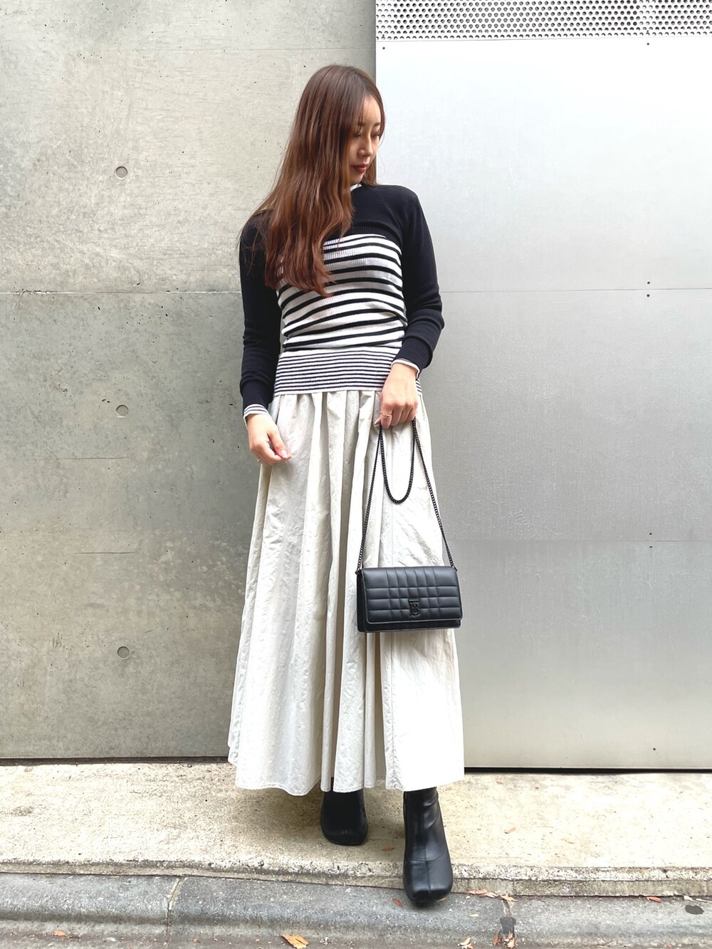 ブラック系のニット/セーター、ホワイト系のニット/セーター、グレー系のスカートを着用したレディースの冬コーディネートの2枚目の写真