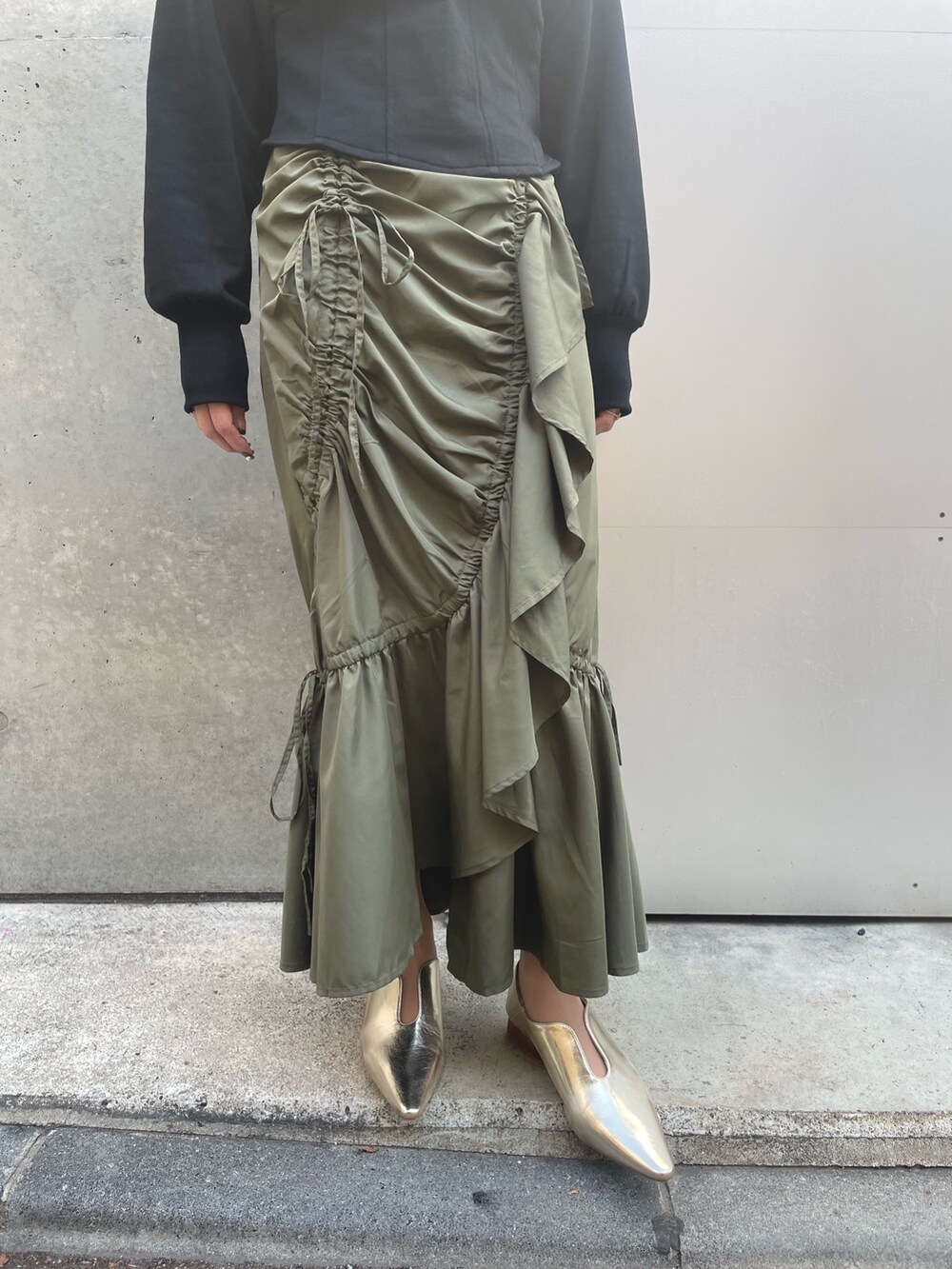 ブラック系のスウェット、グリーン系のスカート、ブラック系のキャップを着用したレディースの春コーディネートの4枚目の写真