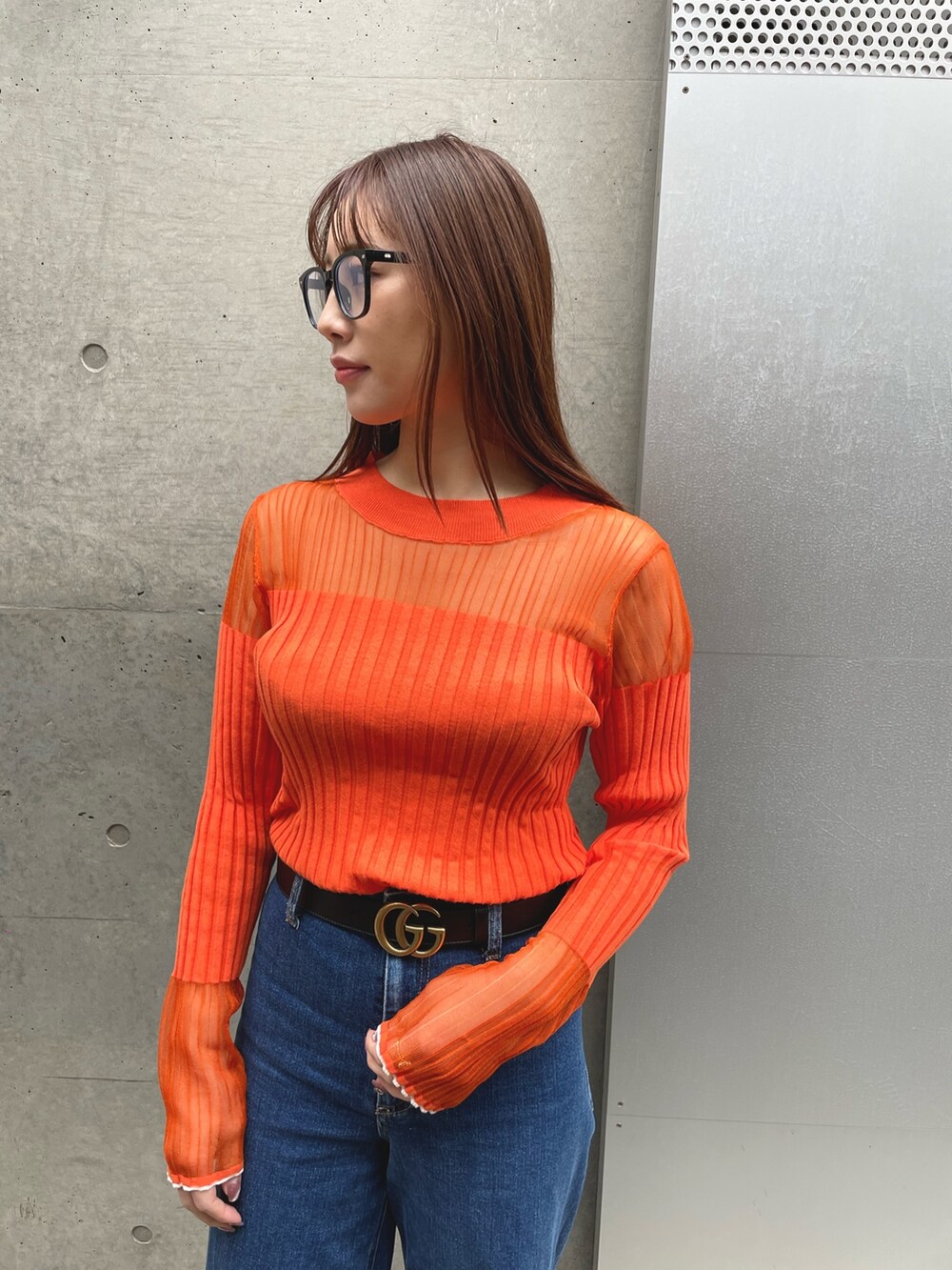 ベージュ系のジャケット/アウター、ブルー系のデニムパンツ、オレンジ系のニット/セーターを着用したレディースの冬コーディネートの2枚目の写真