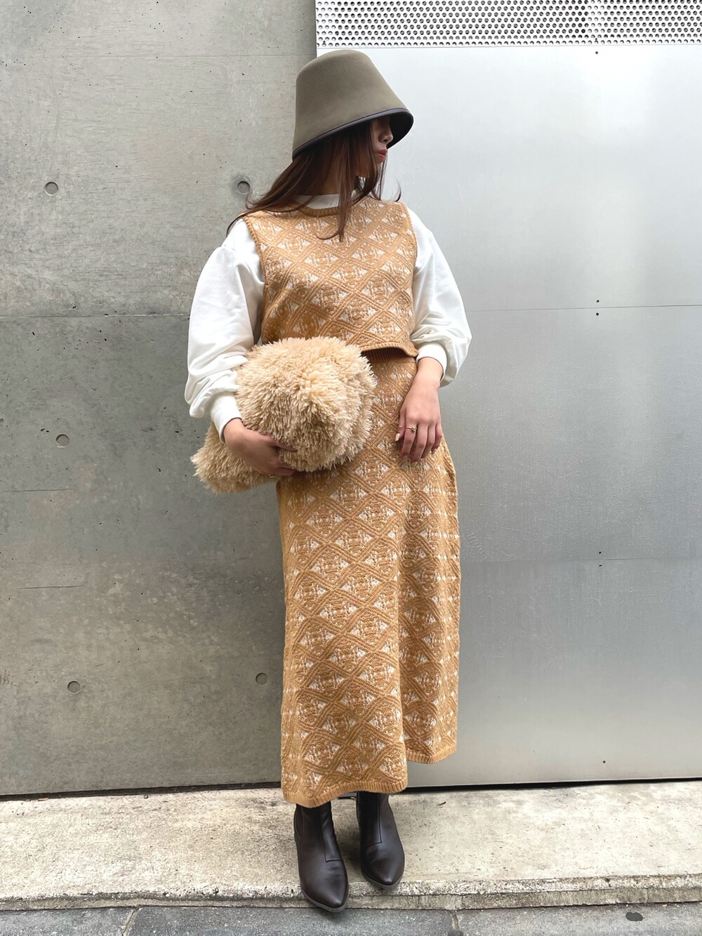 ベージュ系のトートバッグ、ベージュ系のスカート、グリーン系のハットを着用したレディースの冬コーディネートの3枚目の写真