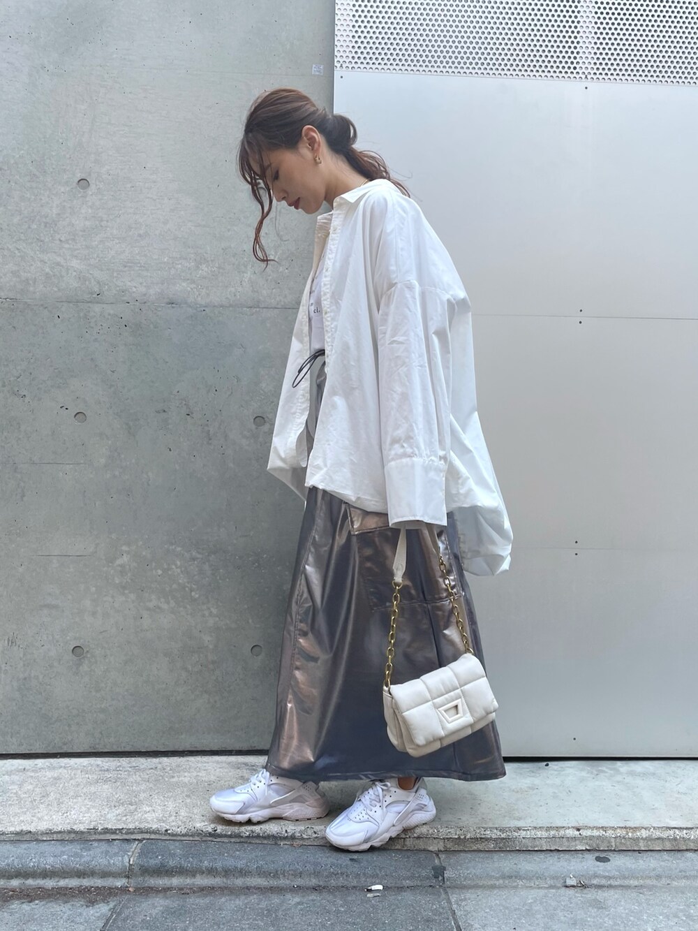 ホワイト系のスニーカー、ホワイト系のバッグ、シルバー系のスカートを着用したレディースの春コーディネートの2枚目の写真