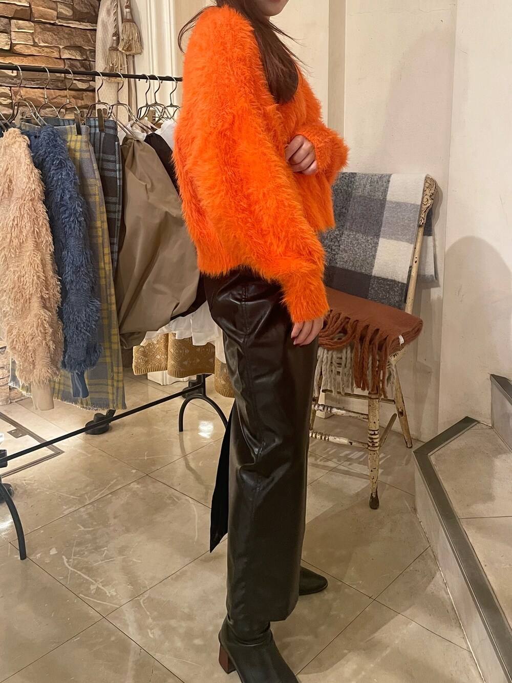 オレンジ系のニット/セーター、ブラック系のスカートを着用したレディースの秋コーディネートの2枚目の写真