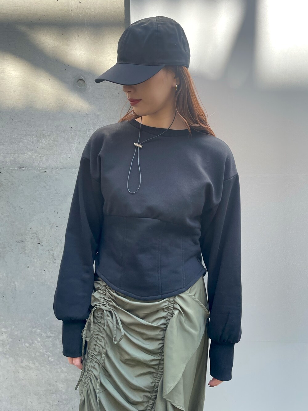 ブラック系のスウェット、グリーン系のスカートを着用したレディースの春コーディネートの2枚目の写真