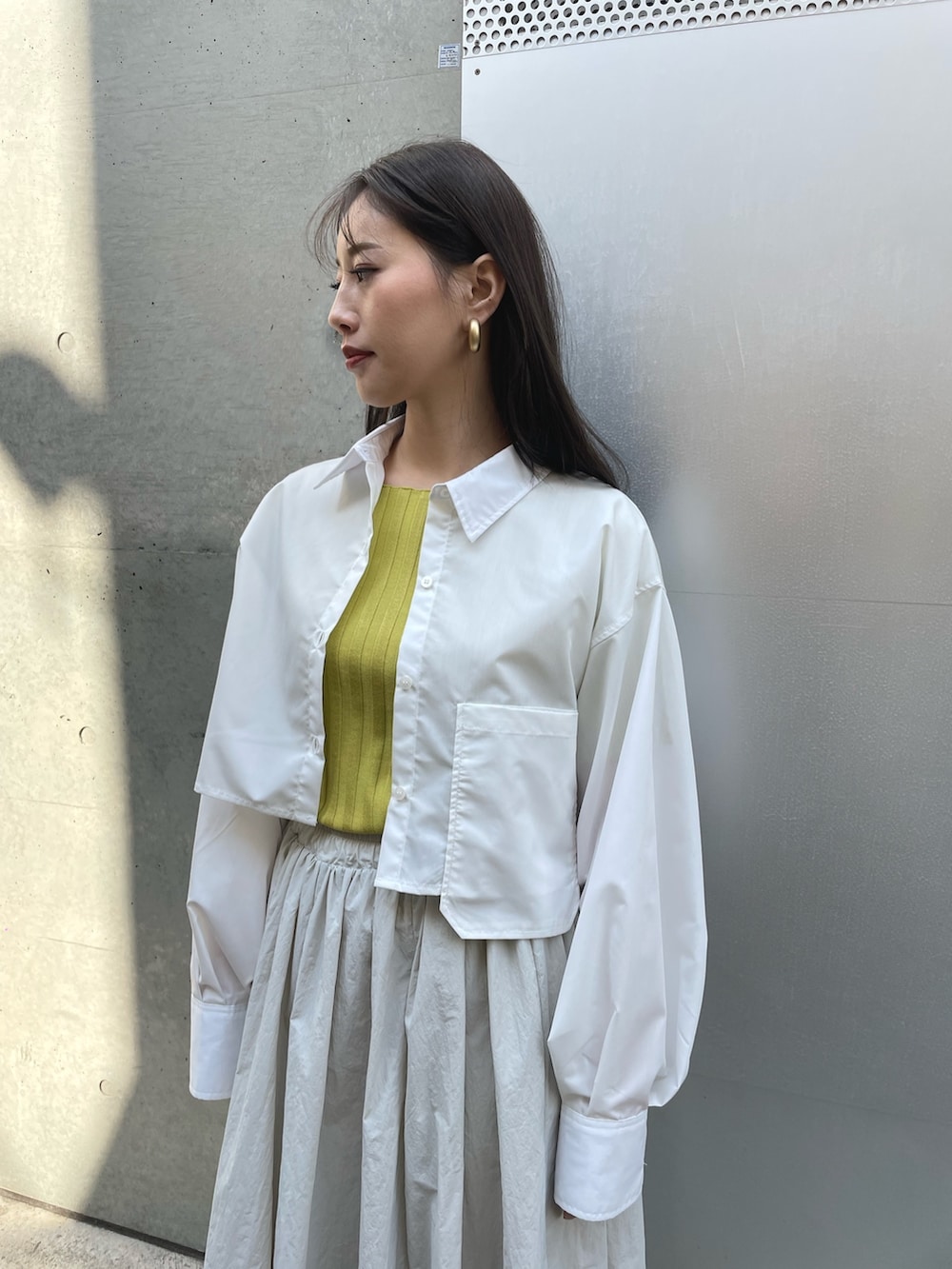 ブラック系のスニーカー、グレー系のスカート、ホワイト系のシャツ/ブラウスを着用したレディースの春コーディネートの3枚目の写真