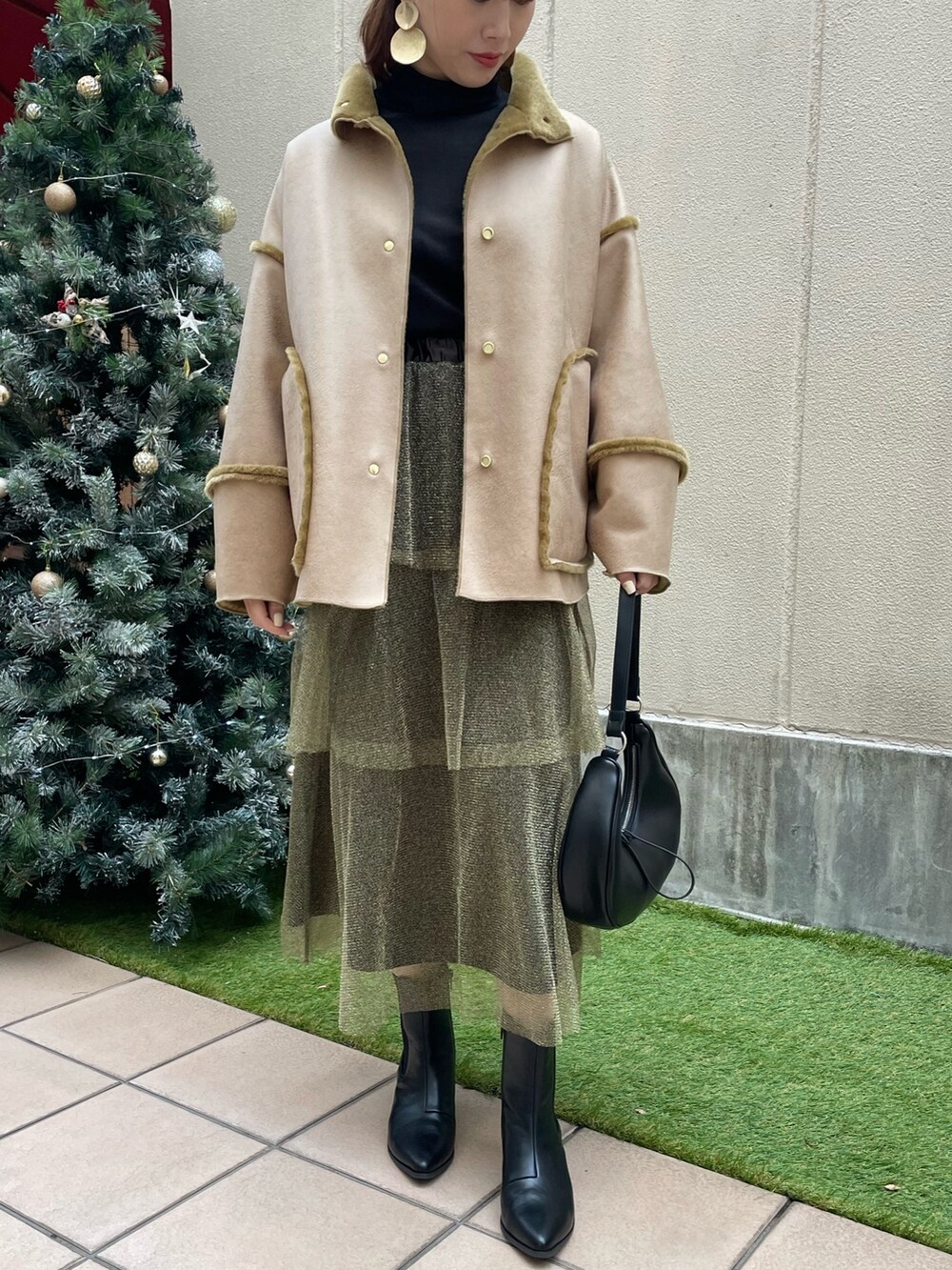 ゴールド系のスカート、ブラック系のショルダーバッグ、ブラック系のTシャツ/カットソーを着用したレディースの冬コーディネートの2枚目の写真