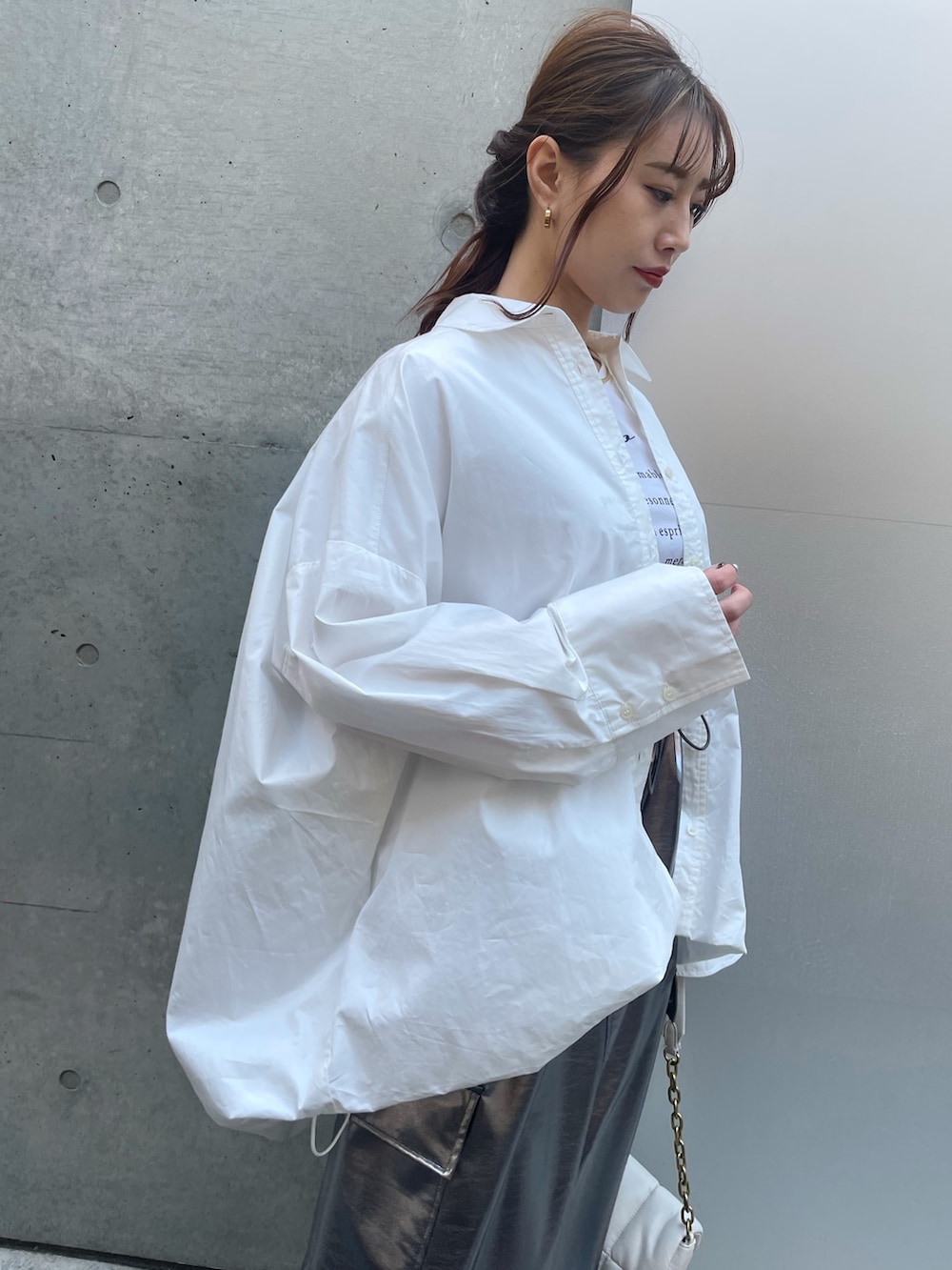 ホワイト系のハンドバッグ、ホワイト系のスニーカー、シルバー系のスカートを着用したレディースの春コーディネートの3枚目の写真