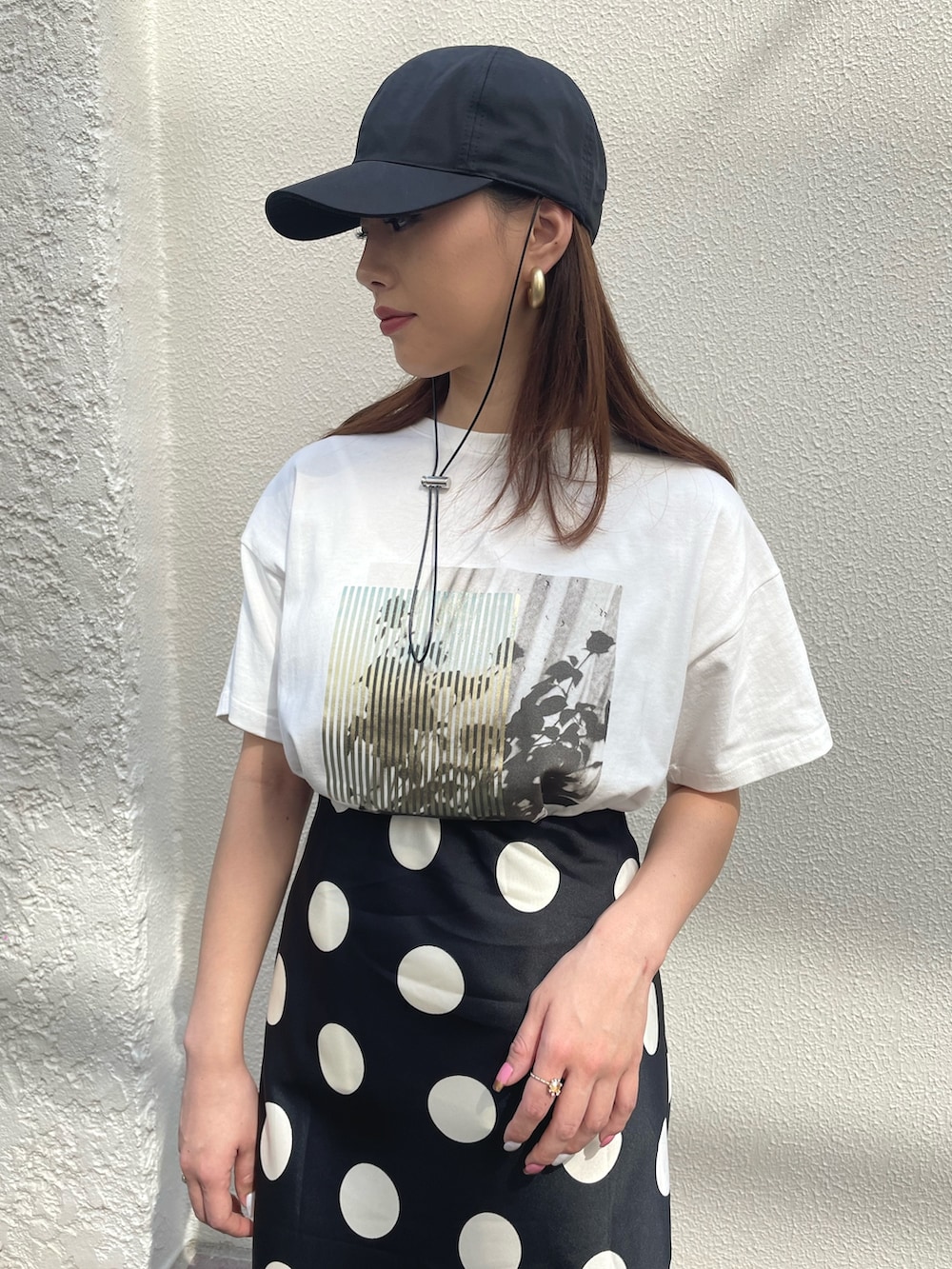 ホワイト系のスニーカー、ブラック系のスカート、ゴールド系のTシャツ/カットソーを着用したレディースの春コーディネートの2枚目の写真