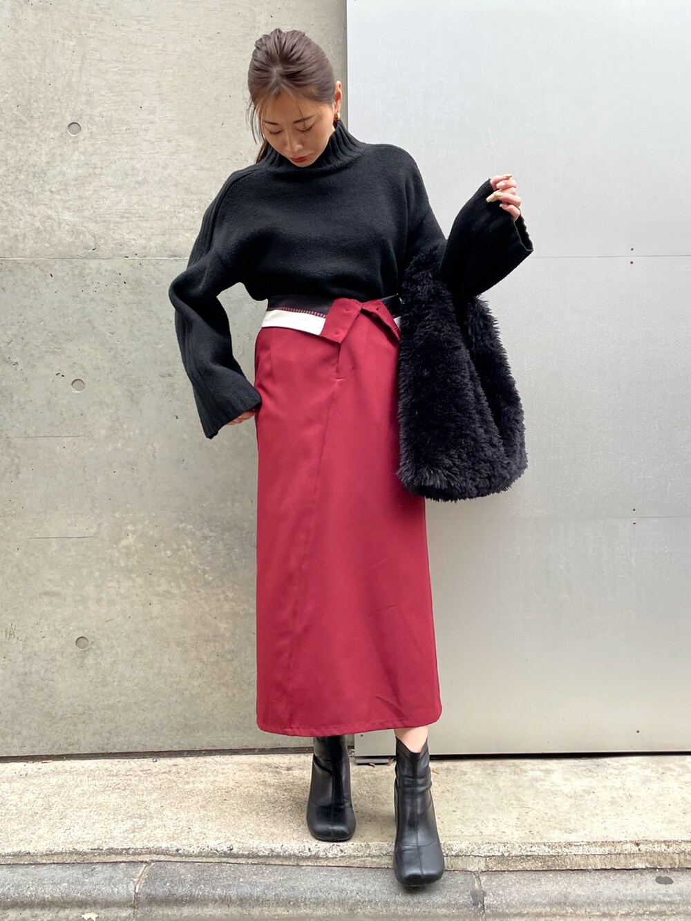ブラック系のブーツ、レッド系のスカート、ブラック系のニット/セーターを着用したレディースの冬コーディネートの2枚目の写真