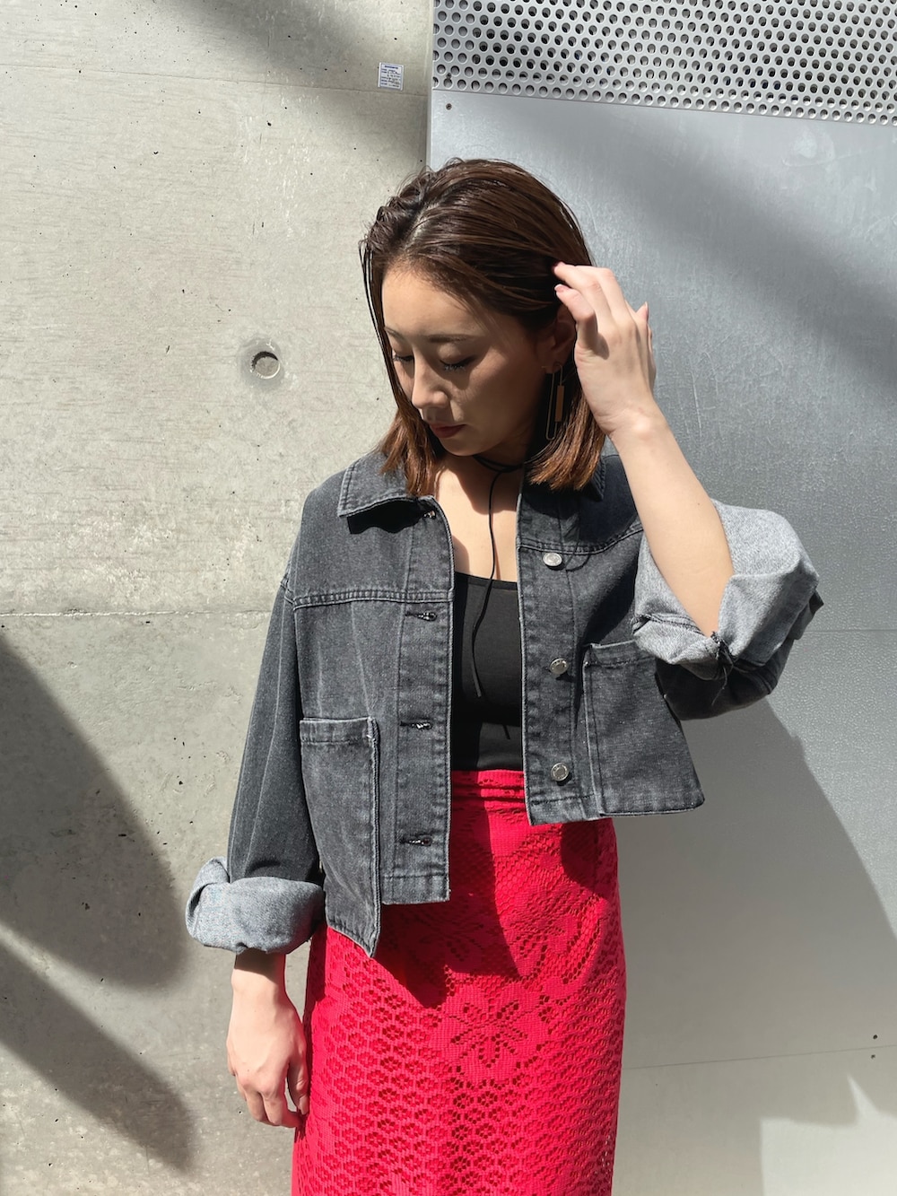 ブラック系のサンダル、レッド系のスカート、ブラック系のデニムジャケットを着用したレディースの春コーディネートの3枚目の写真