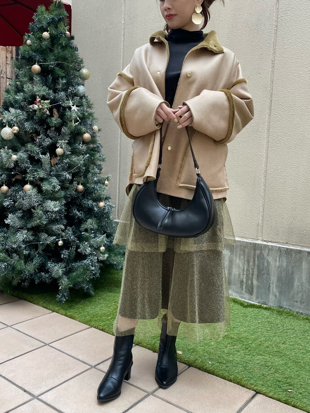 ゴールド系のスカート、ブラック系のショルダーバッグ、ブラック系のTシャツ/カットソーを着用したレディースの冬コーディネートの3枚目の写真