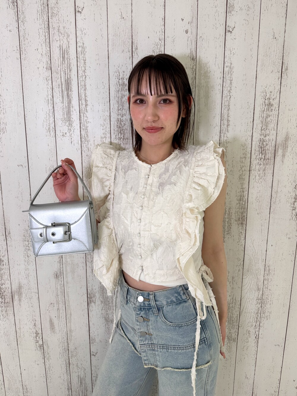 ホワイト系のベスト、ブルー系のデニムパンツ、シルバー系のショルダーバッグを着用したレディースの春コーディネートの4枚目の写真