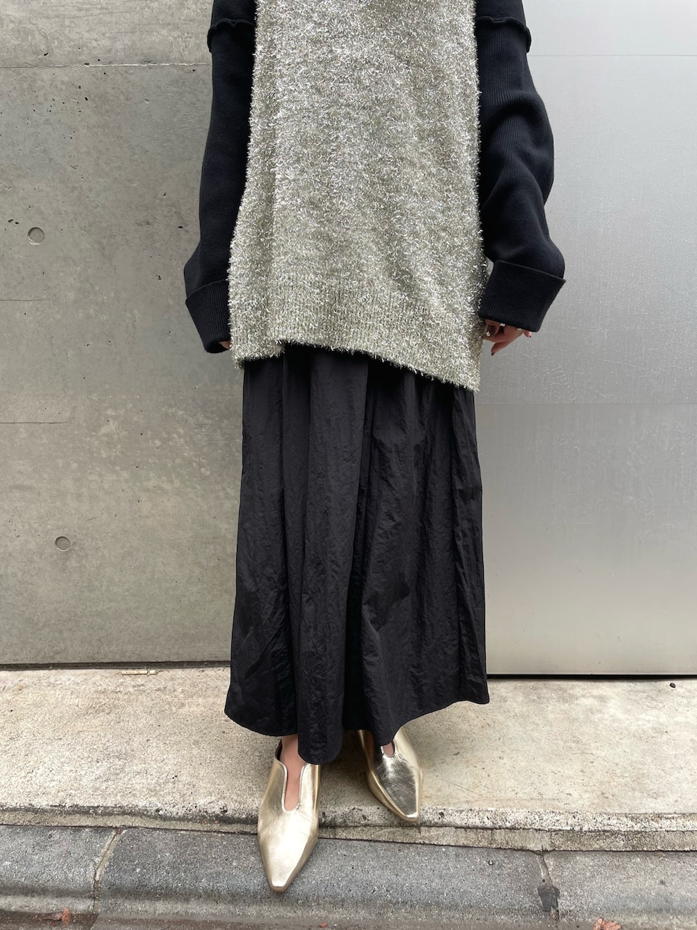 ゴールド系のベスト、ブラック系のスカートを着用したレディースの冬コーディネートの3枚目の写真