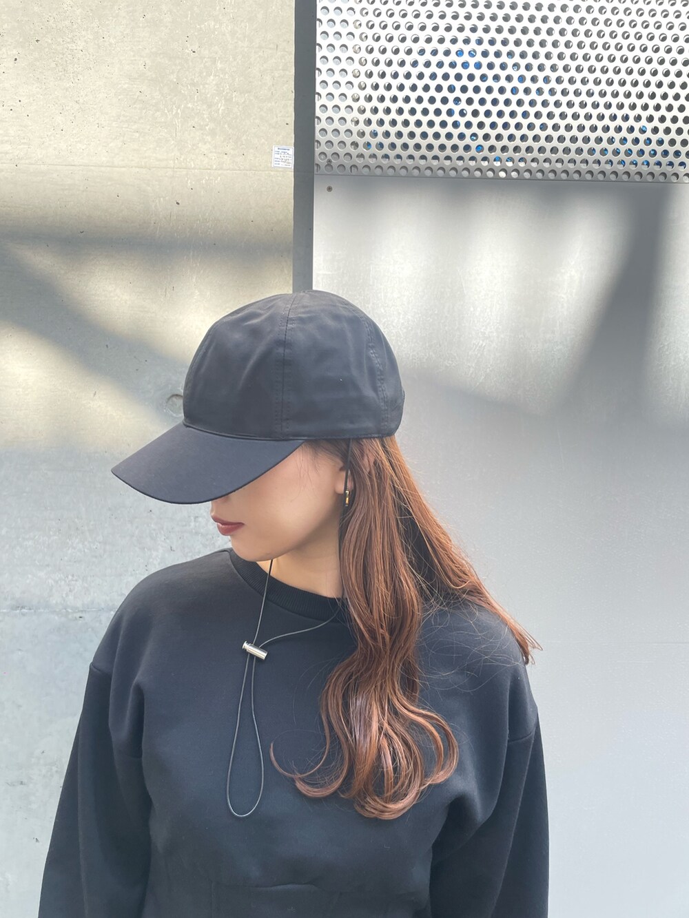 ブラック系のスウェット、グリーン系のスカート、ブラック系のキャップを着用したレディースの春コーディネートの6枚目の写真