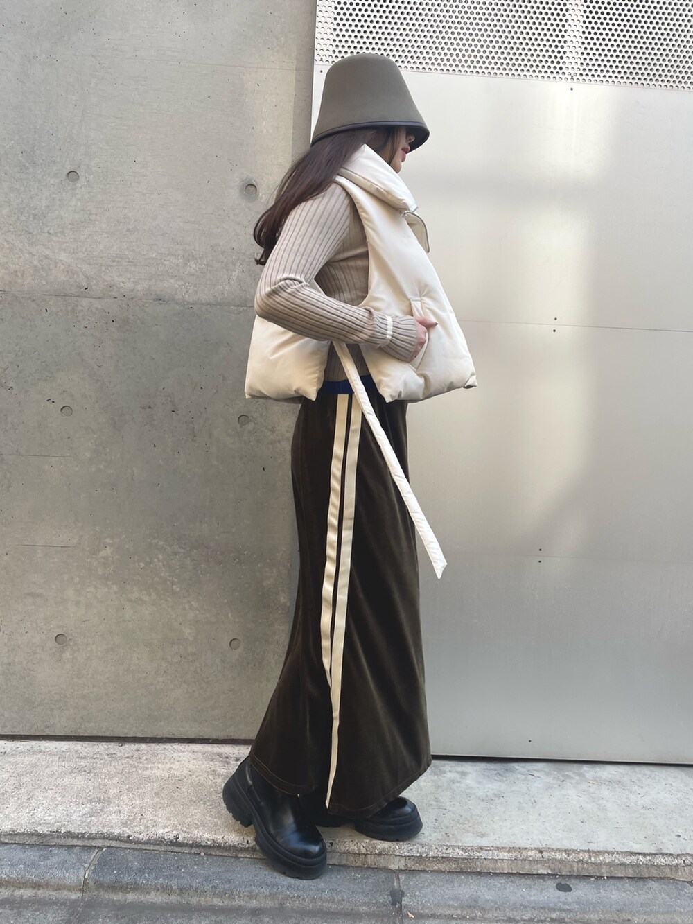 グリーン系のスカート、ベージュ系のニット/セーター、ホワイト系のダウンベストを着用したレディースの冬コーディネートの6枚目の写真