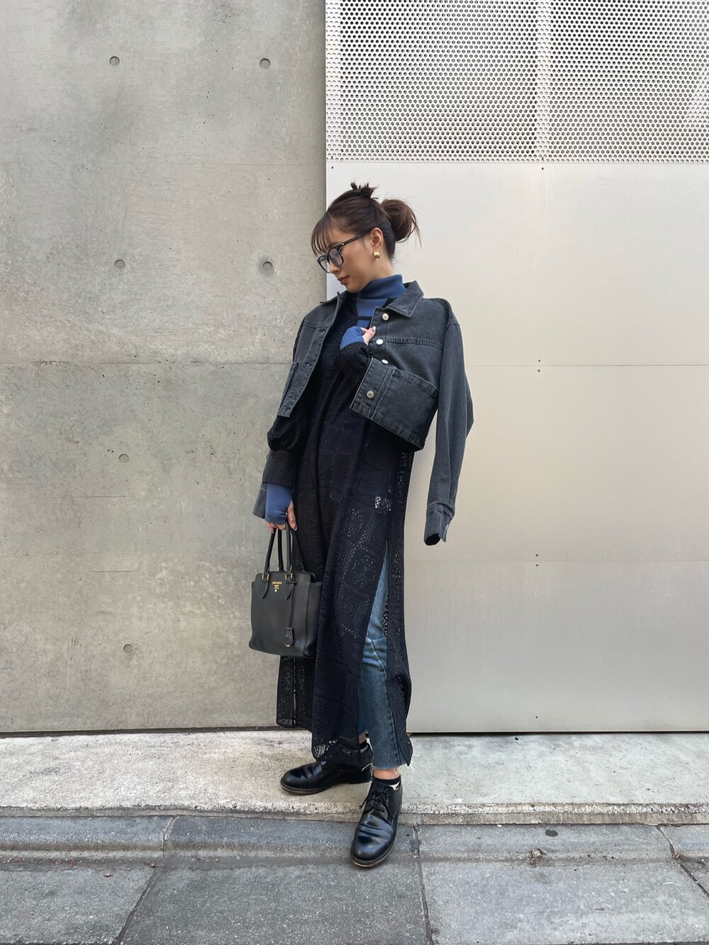 ブラック系のデニムジャケット、ブルー系のニット/セーター、ブラック系のワンピースを着用したレディースの冬コーディネートの2枚目の写真