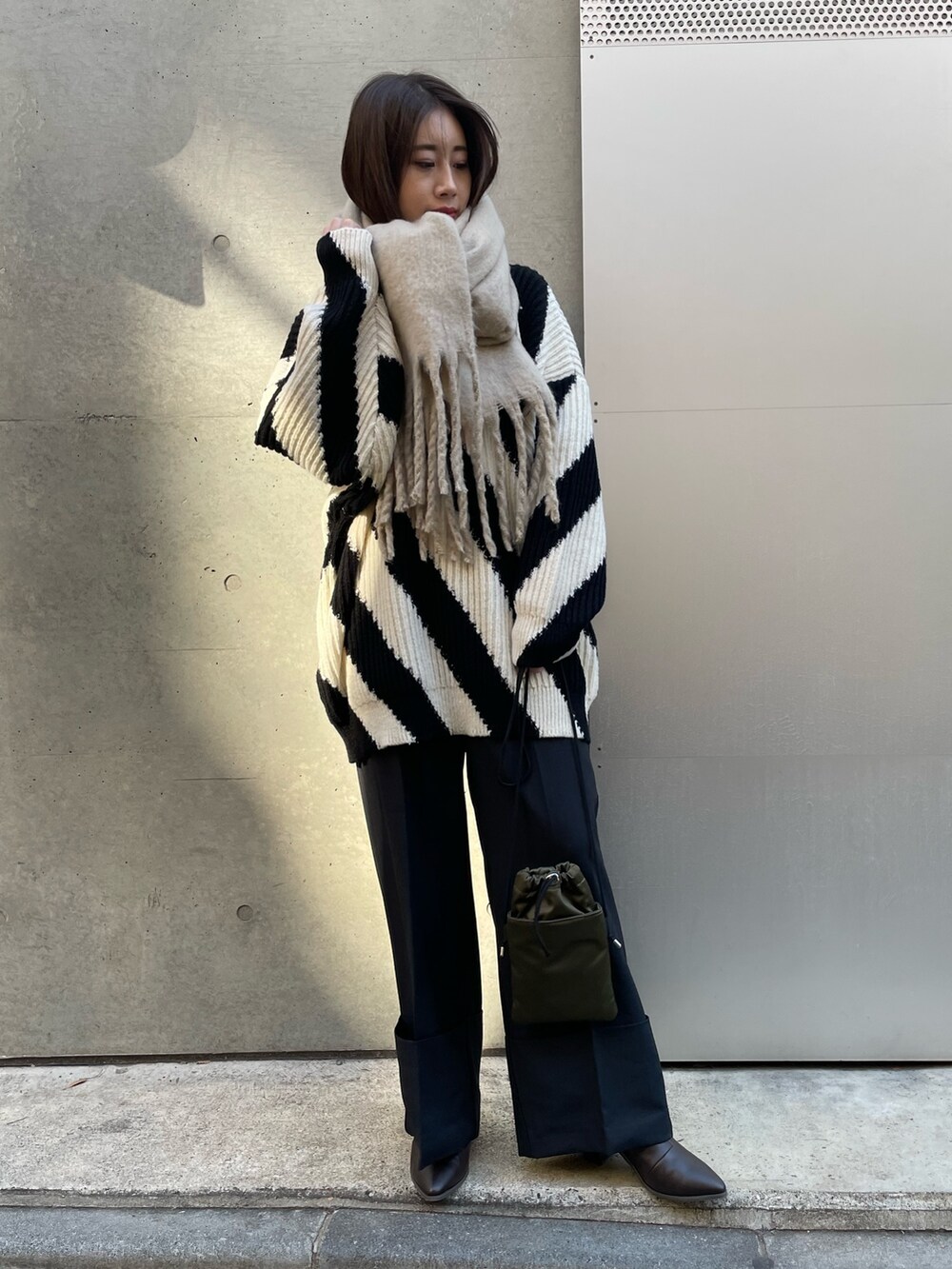 ブラック系のその他パンツ、ブラック系のニット/セーター、ベージュ系のストール/ショールを着用したレディースの冬コーディネートの2枚目の写真