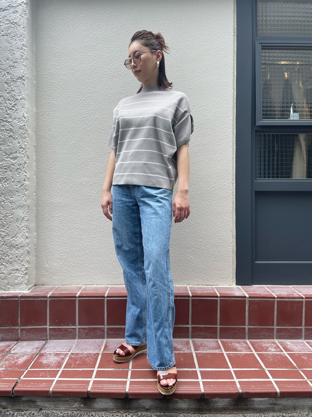 グレー系のTシャツ/カットソー、ブルー系のデニムパンツ、ブラウン系のサングラスを着用したレディースの夏コーディネートの2枚目の写真