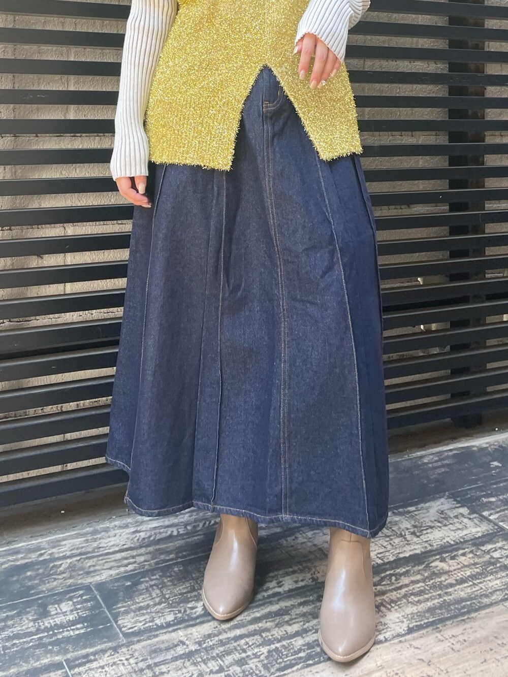 ブルー系のデニムスカート、ホワイト系のニット/セーター、ゴールド系のベストを着用したレディースの冬コーディネートの9枚目の写真