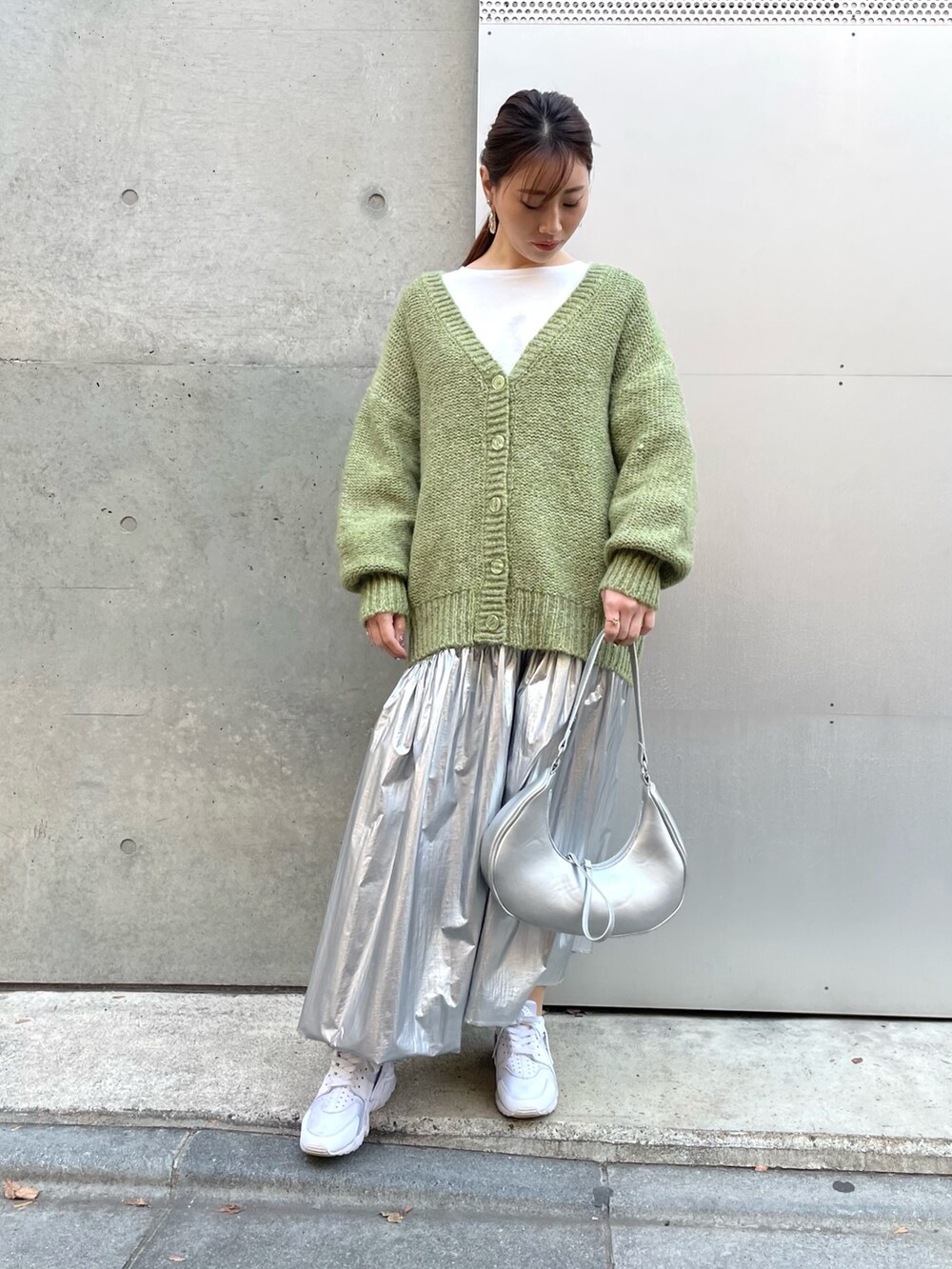 シルバー系のスカート、ホワイト系のスニーカー、ホワイト系のTシャツ/カットソーを着用したレディースの冬コーディネートの2枚目の写真