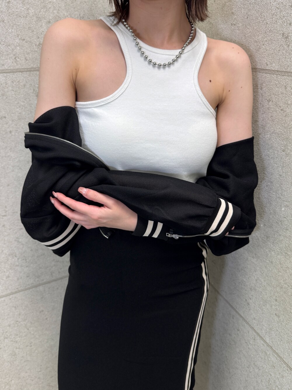 ブラック系のスカート、ホワイト系のタンクトップ、ブラック系のブルゾンを着用したレディースの春コーディネートの3枚目の写真