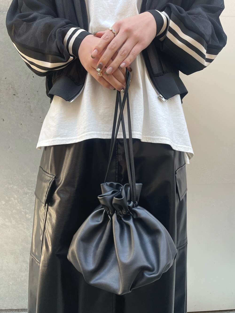 ブラック系のショルダーバッグ、ブラック系のスカート、ブラック系のブルゾンを着用したレディースの春コーディネートの6枚目の写真